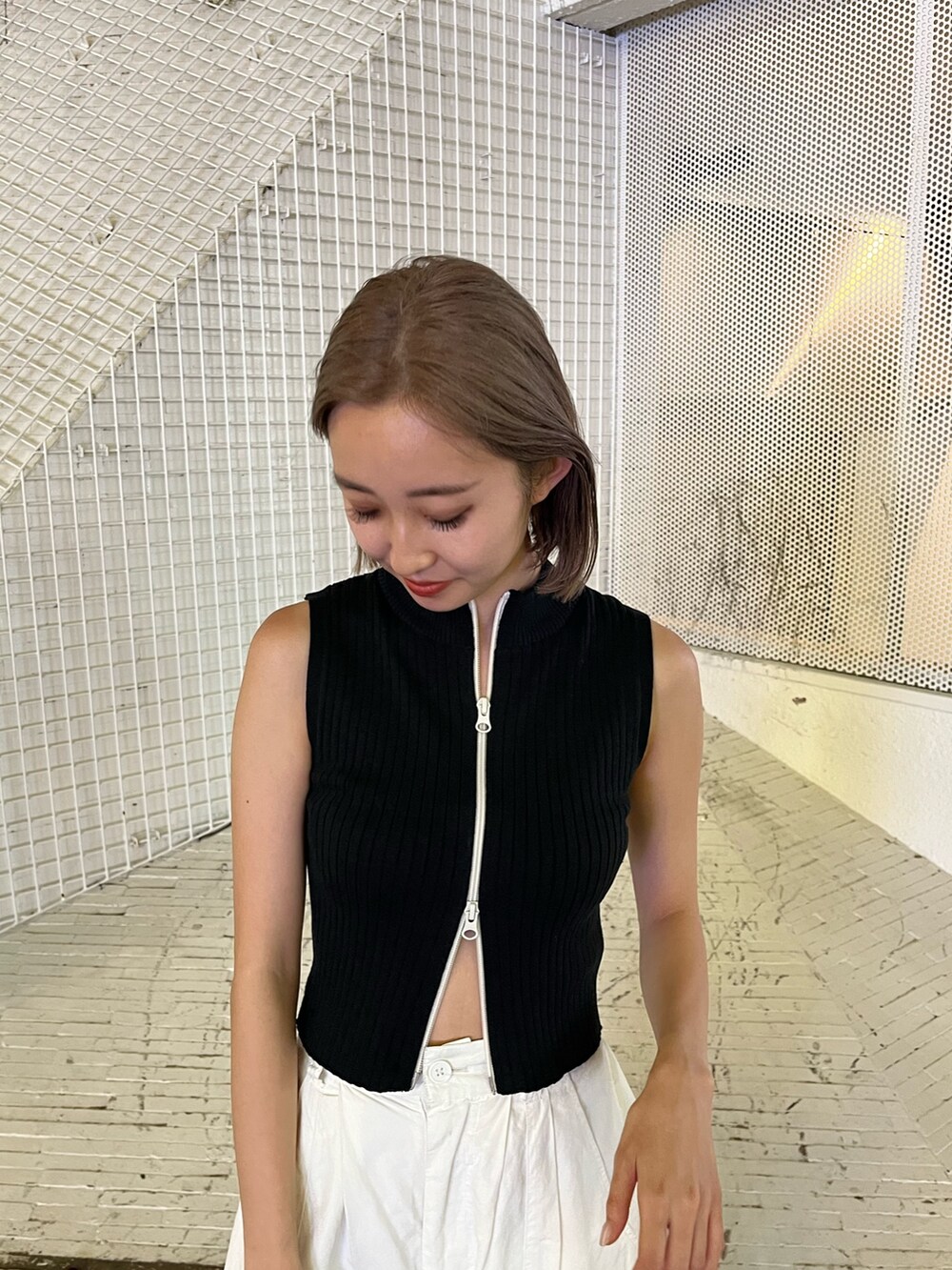 ホワイト系のカーゴパンツ、ブラック系のタンクトップ、ホワイト系のブーツを着用したレディースの夏コーディネートの7枚目の写真