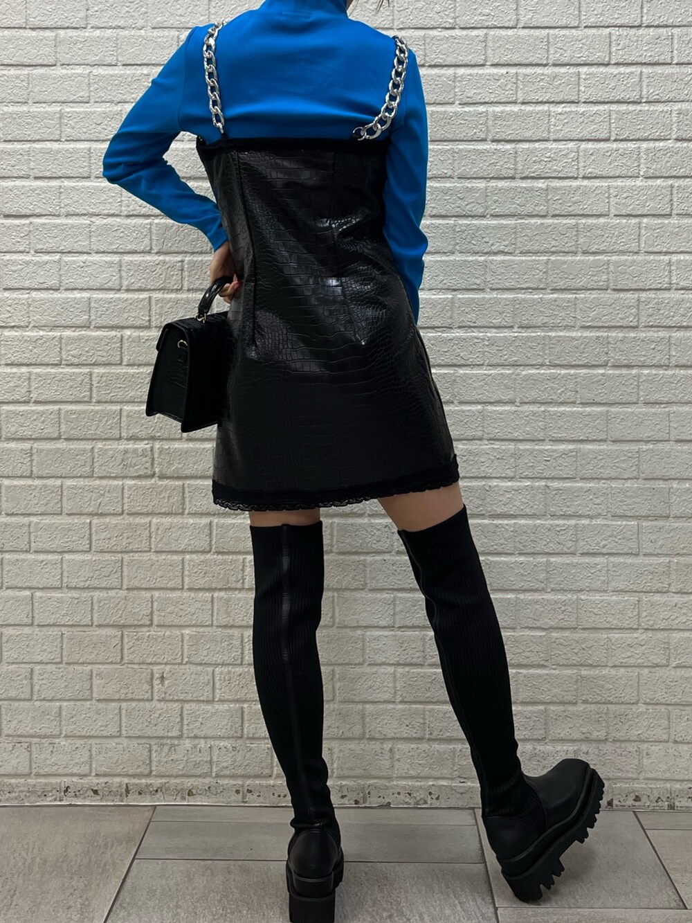 ブラック系のブーツ、ブラック系のワンピース、ブルー系のTシャツ/カットソーを着用したレディースの秋コーディネートの3枚目の写真