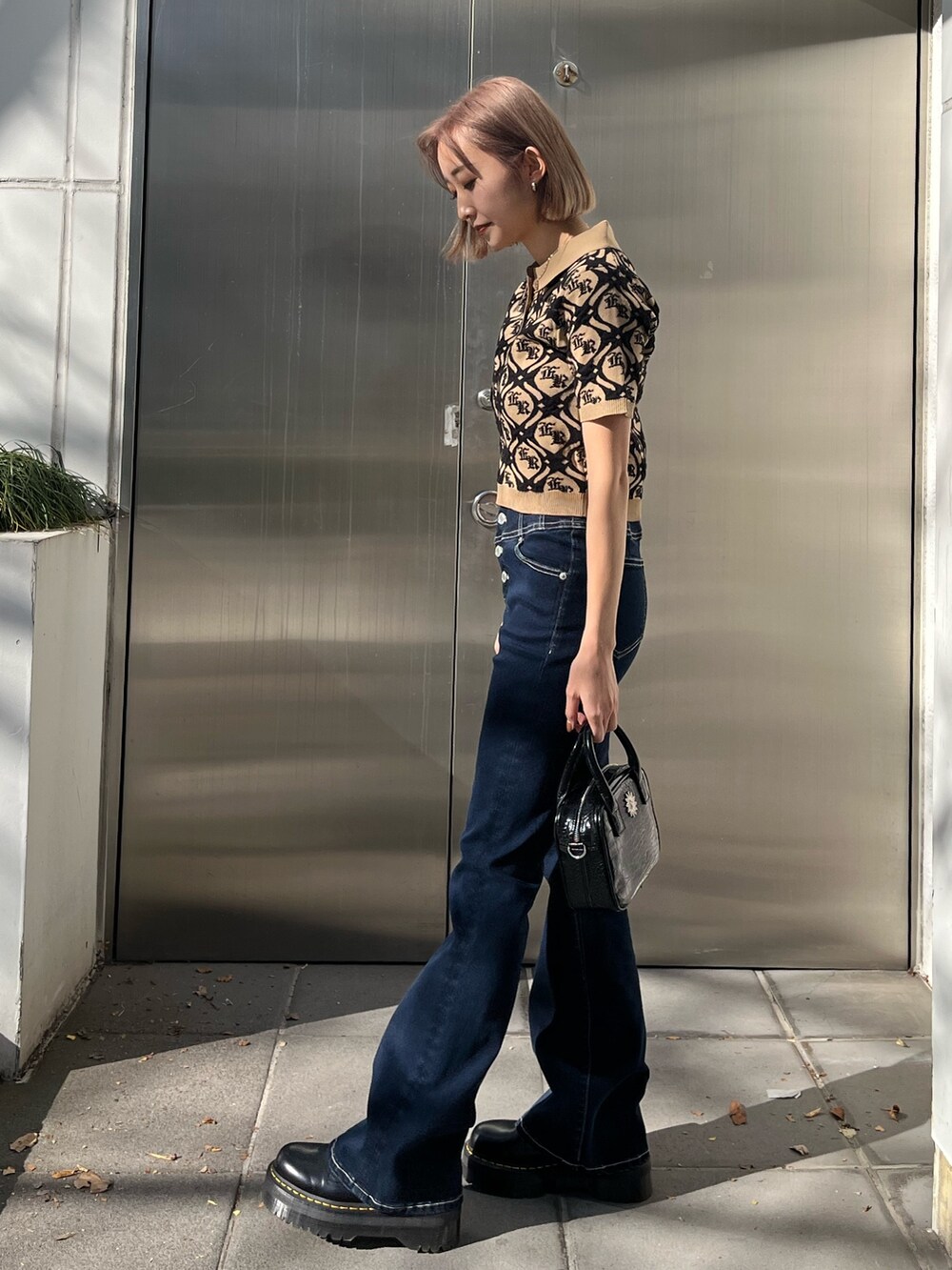 ブルー系のショルダーバッグ、ブルー系のデニムパンツ、ベージュ系のニット/セーターを着用したレディースの冬コーディネートの2枚目の写真