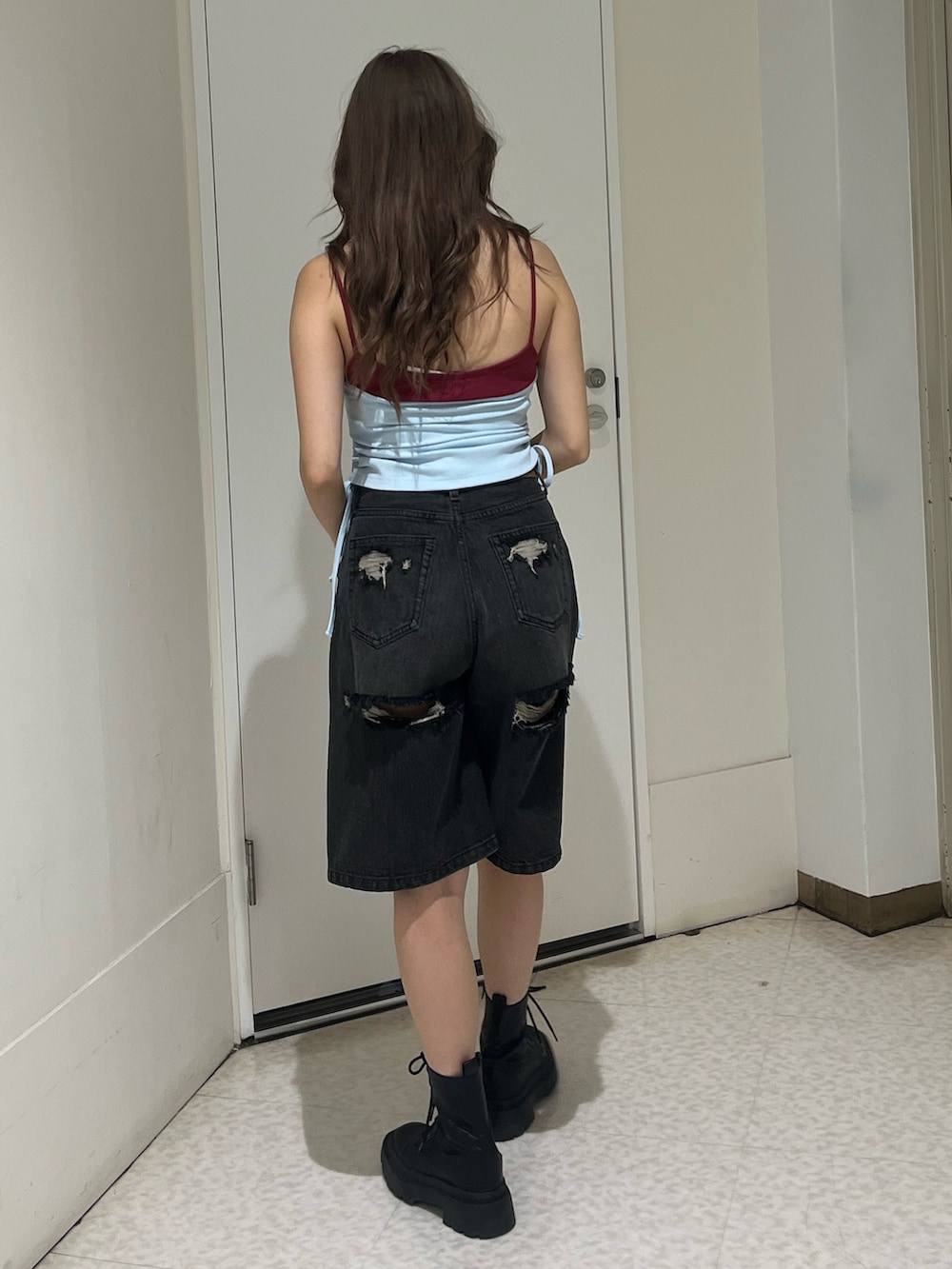 ブルー系のタンクトップ、ブラック系のデニムパンツ、ブラック系のブーツを着用したレディースの夏コーディネートの3枚目の写真