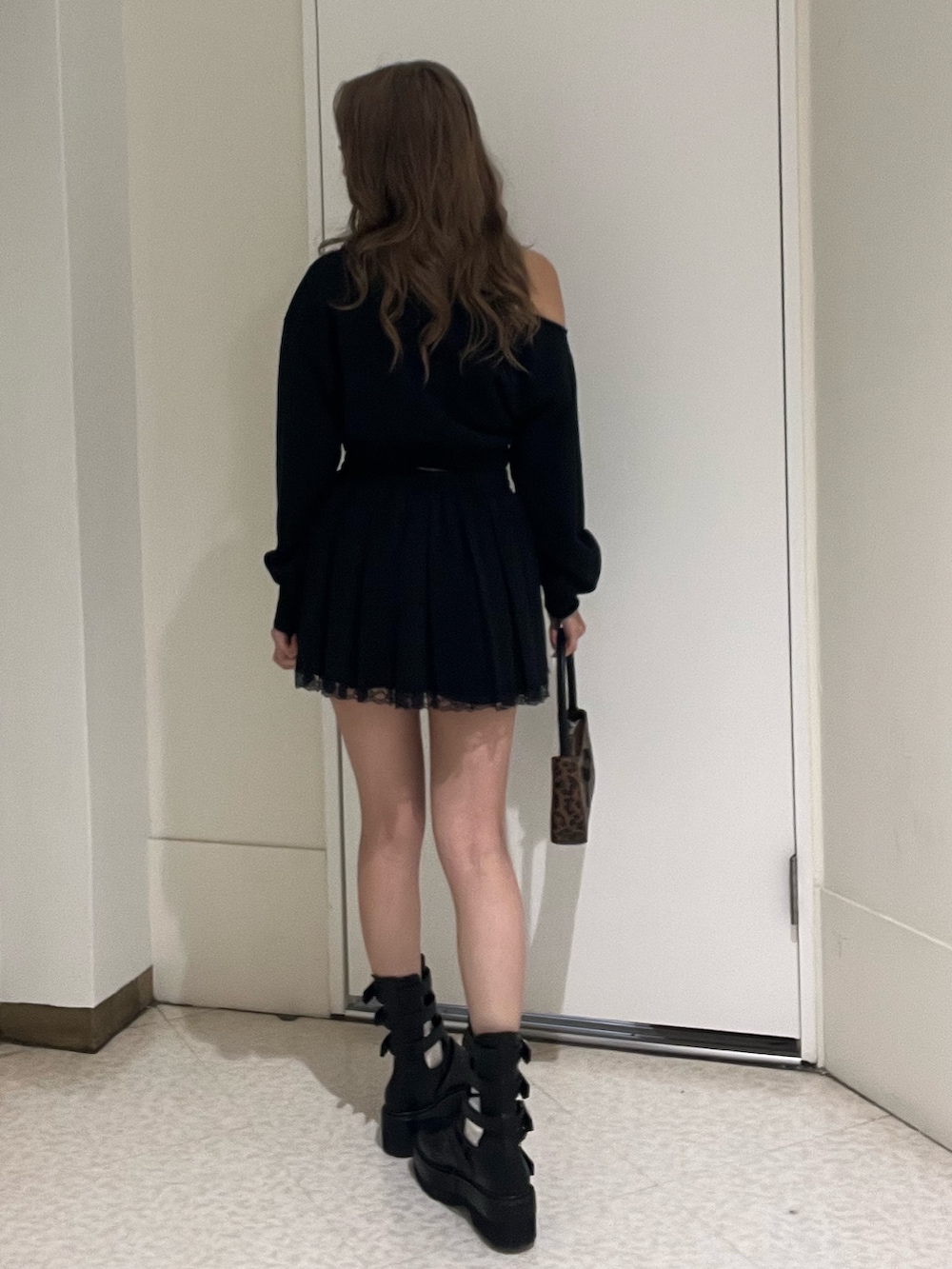 ブラック系のスウェット、ブラック系のスカート、ブラック系のブーツを着用したレディースの春コーディネートの3枚目の写真
