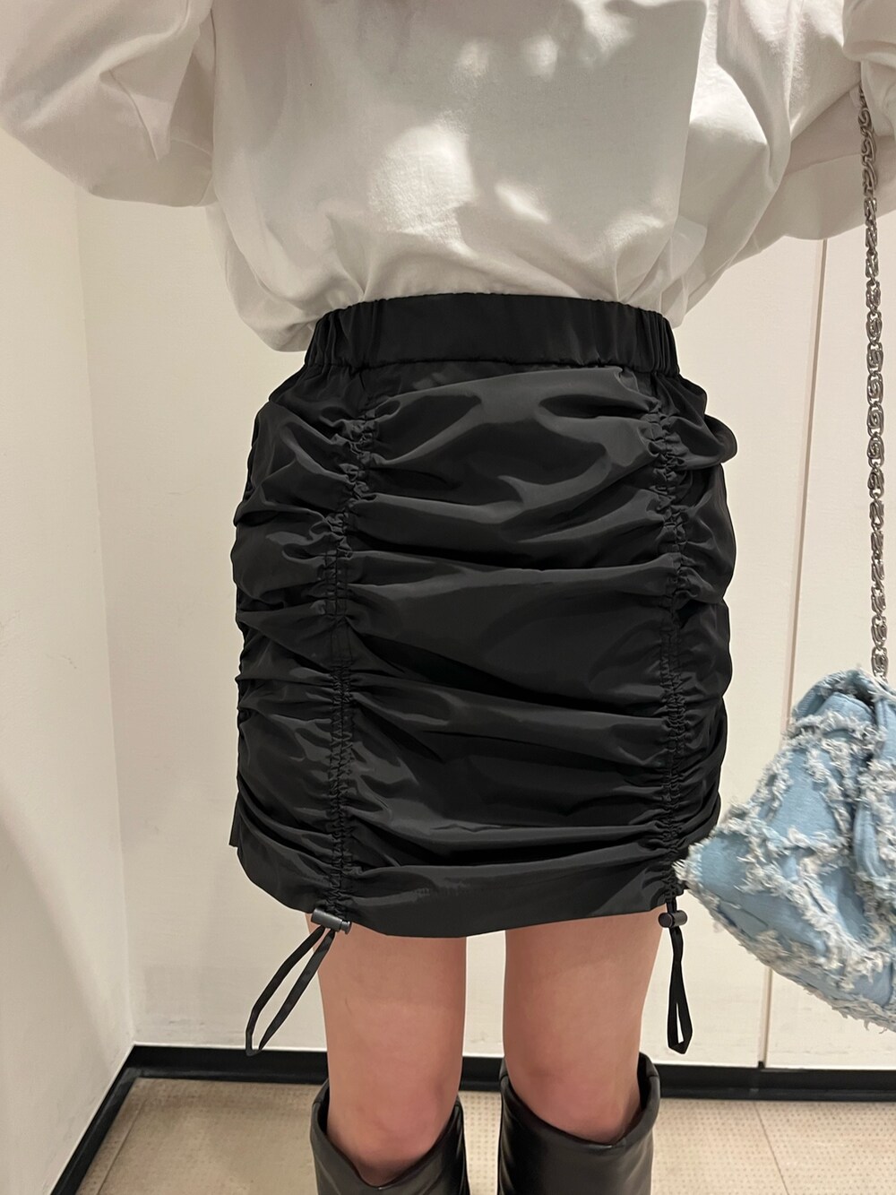 ホワイト系のブーツ、ブルー系のショルダーバッグ、ホワイト系のTシャツ/カットソーを着用したレディースの冬コーディネートの6枚目の写真