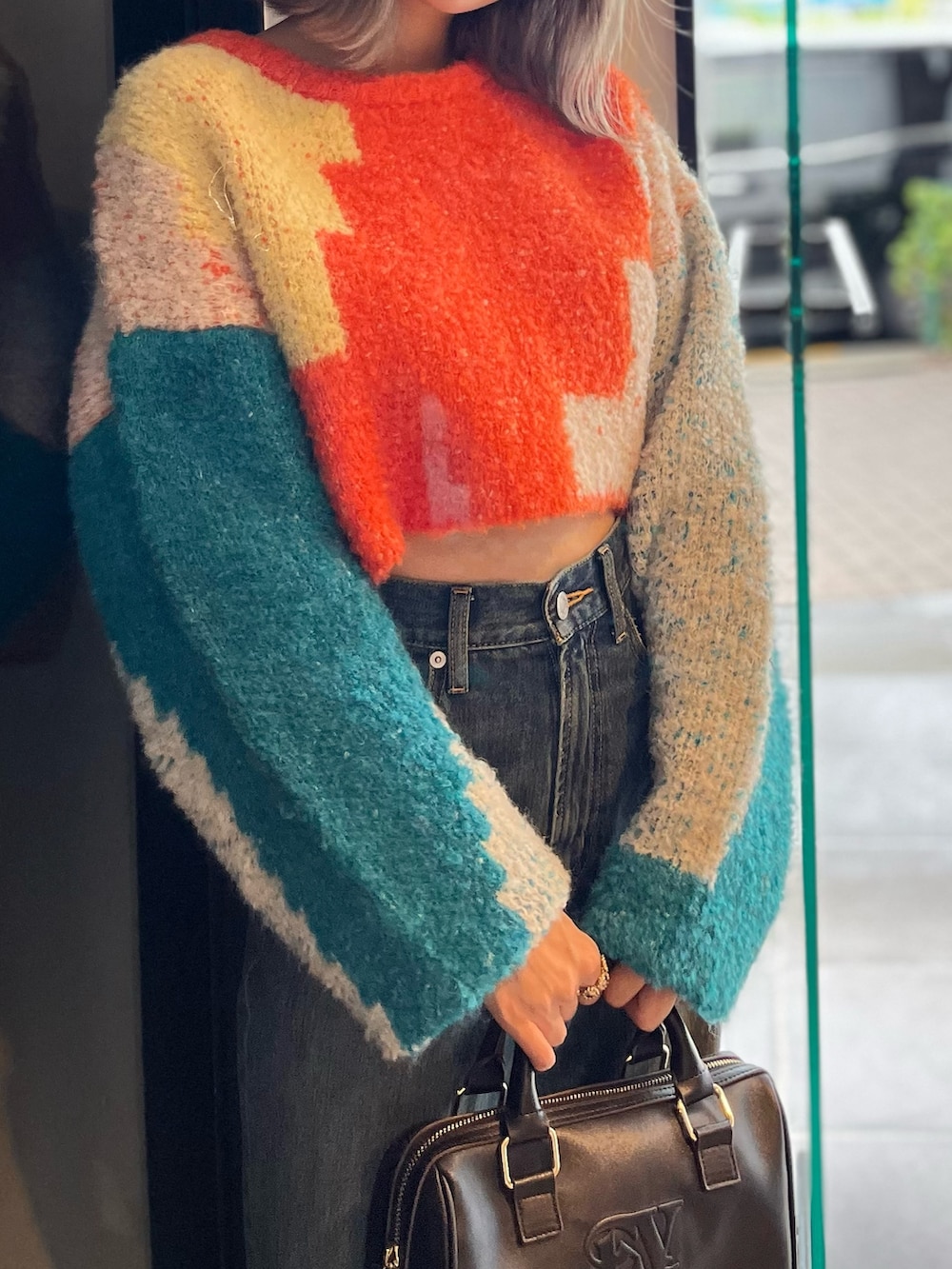 ブラック系のボストンバッグ、ブルー系のニット/セーター、ブルー系のデニムパンツを着用したレディースの冬コーディネートの7枚目の写真