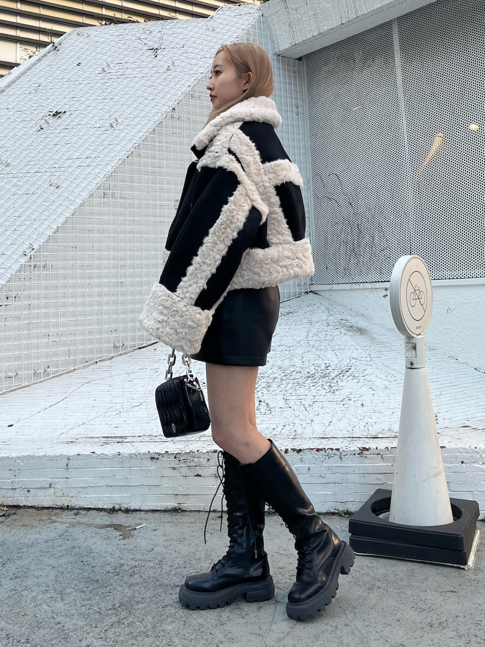 ブラック系のブーツ、シルバー系のショルダーバッグ、グリーン系のムートンコートを着用したレディースの冬コーディネートの2枚目の写真