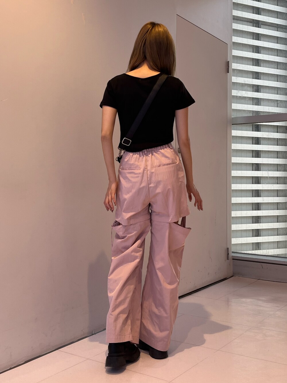 ピンク系のカーゴパンツ、シルバー系のボディバッグ/ウエストポーチ、ブラック系のTシャツ/カットソーを着用したレディースの春コーディネートの2枚目の写真