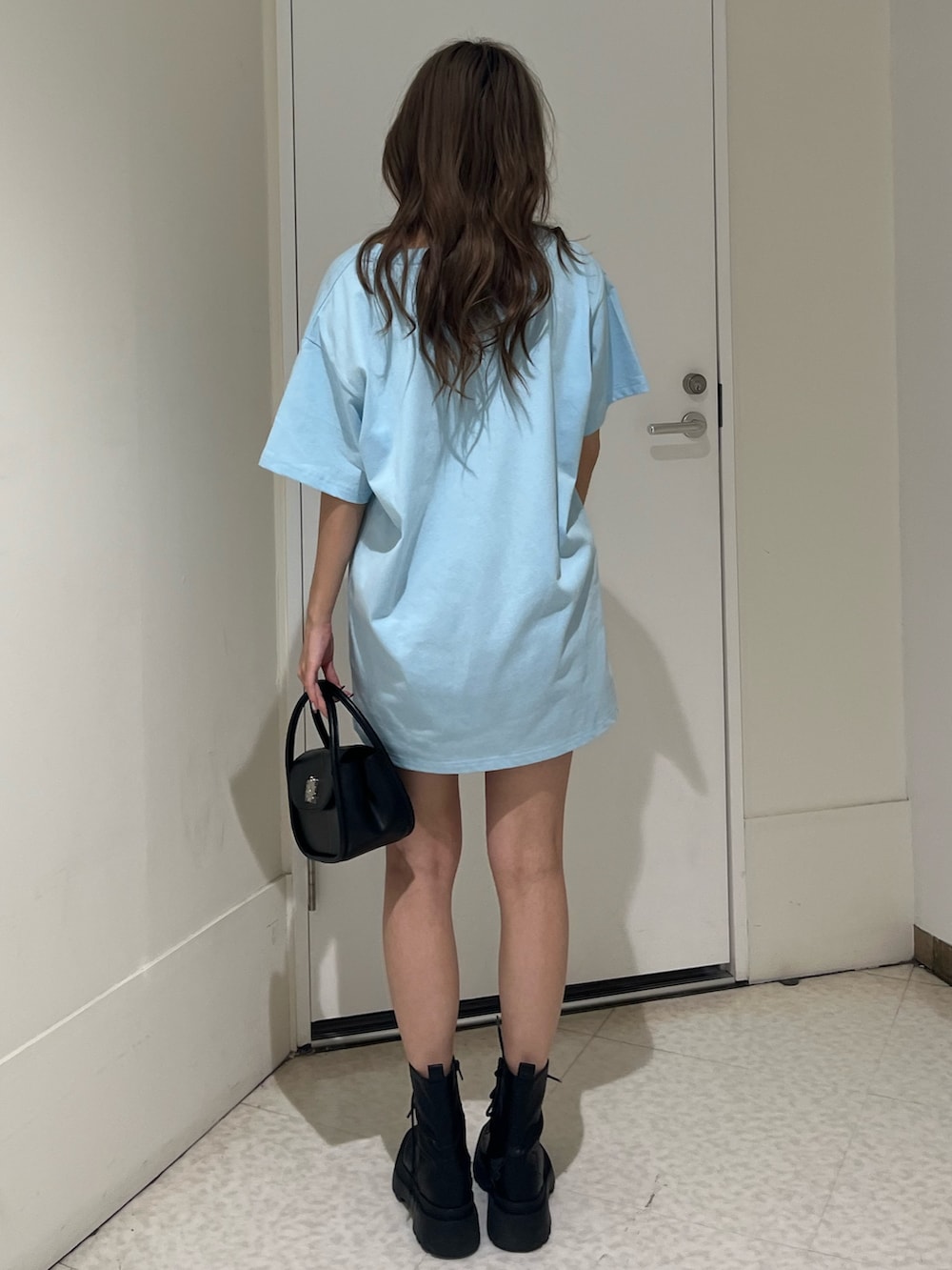 ブラック系のハンドバッグ、ブラック系のブーツ、ブルー系のTシャツ/カットソーを着用したレディースの春コーディネートの4枚目の写真