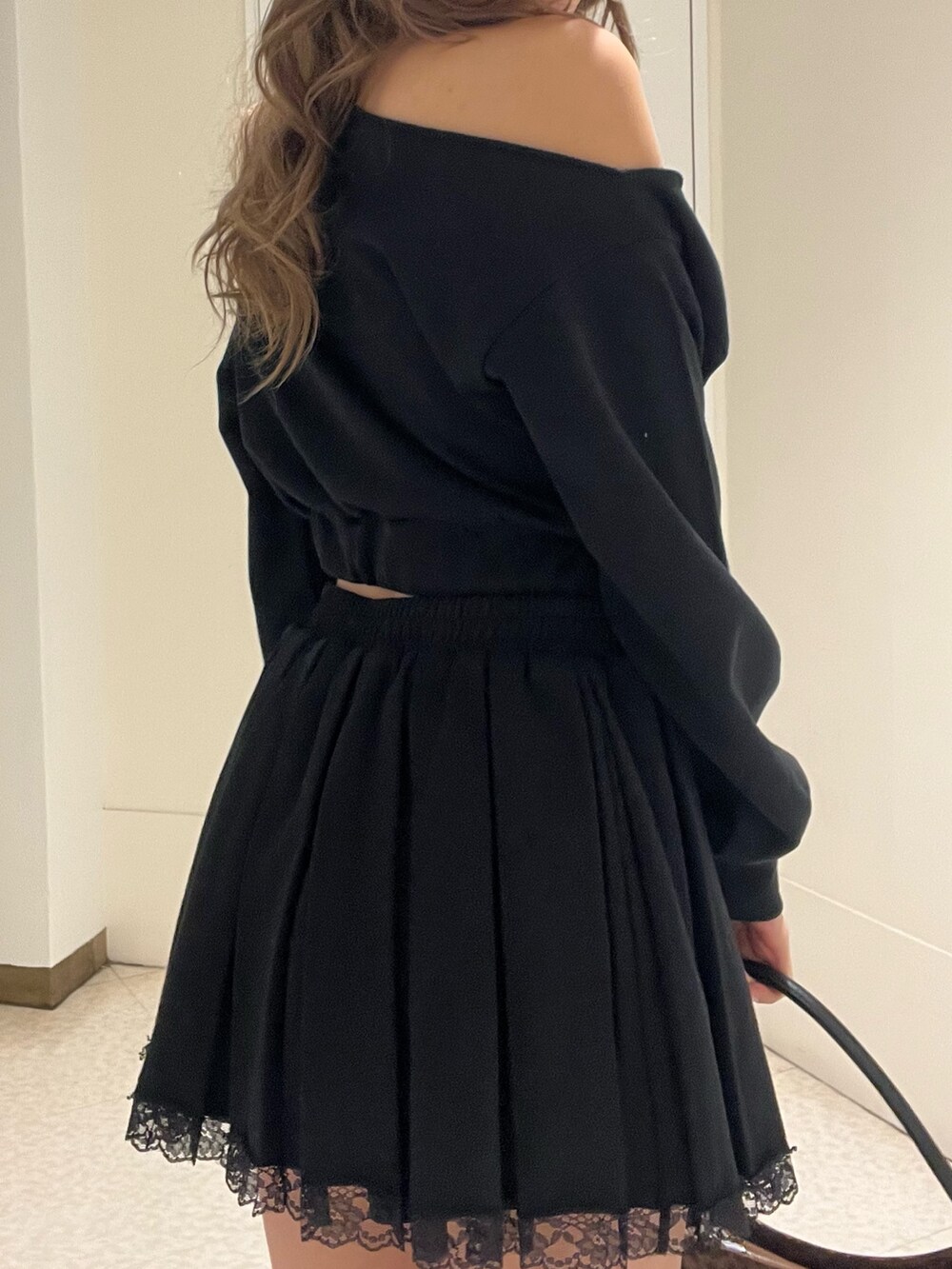 ブラック系のスウェット、ブラック系のスカート、ブラック系のブーツを着用したレディースの春コーディネートの6枚目の写真