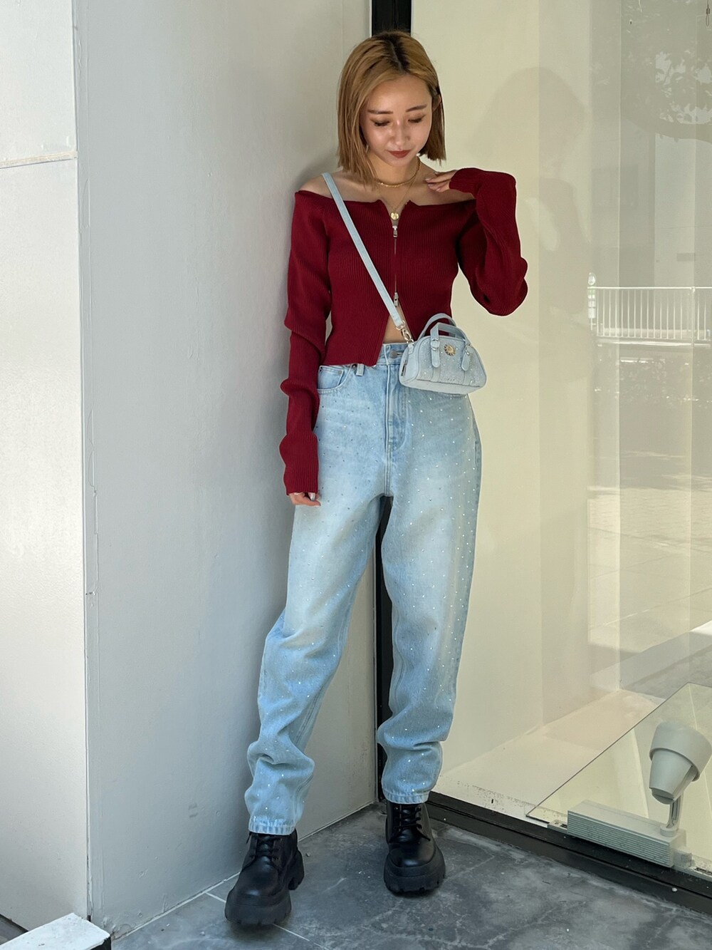 ブルー系のデニムパンツ、レッド系のニット/セーター、ブルー系のハンドバッグを着用したレディースの秋コーディネートの6枚目の写真