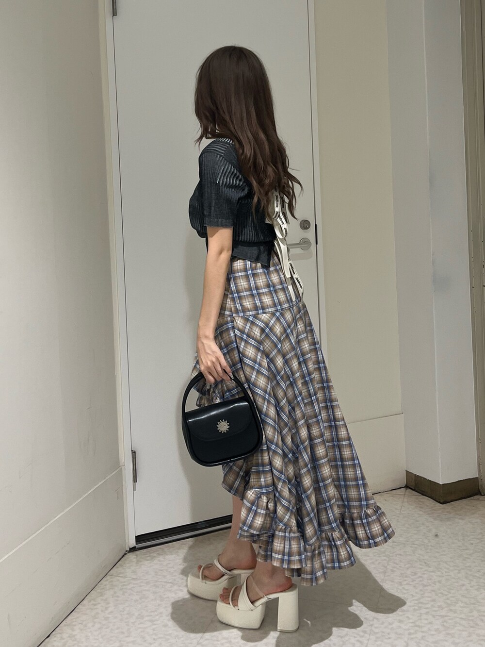 ベージュ系のスカート、ブラック系のハンドバッグ、ブラック系のサンダルを着用したレディースの夏コーディネートの2枚目の写真