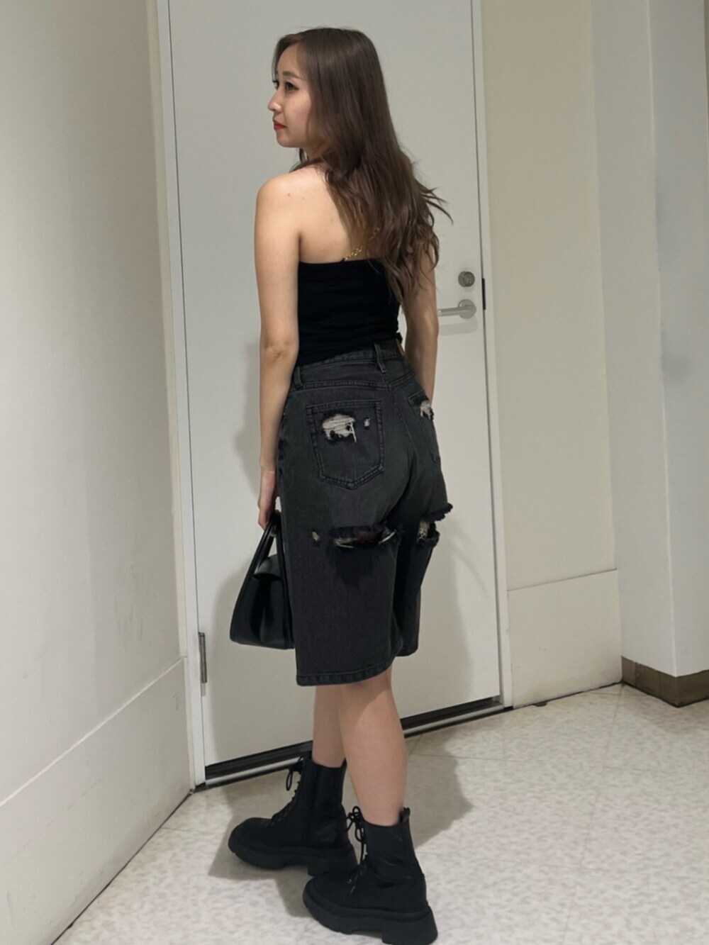 ブラック系のブーツ、ブラック系のハンドバッグ、ブラック系のデニムパンツを着用したレディースの夏コーディネートの5枚目の写真