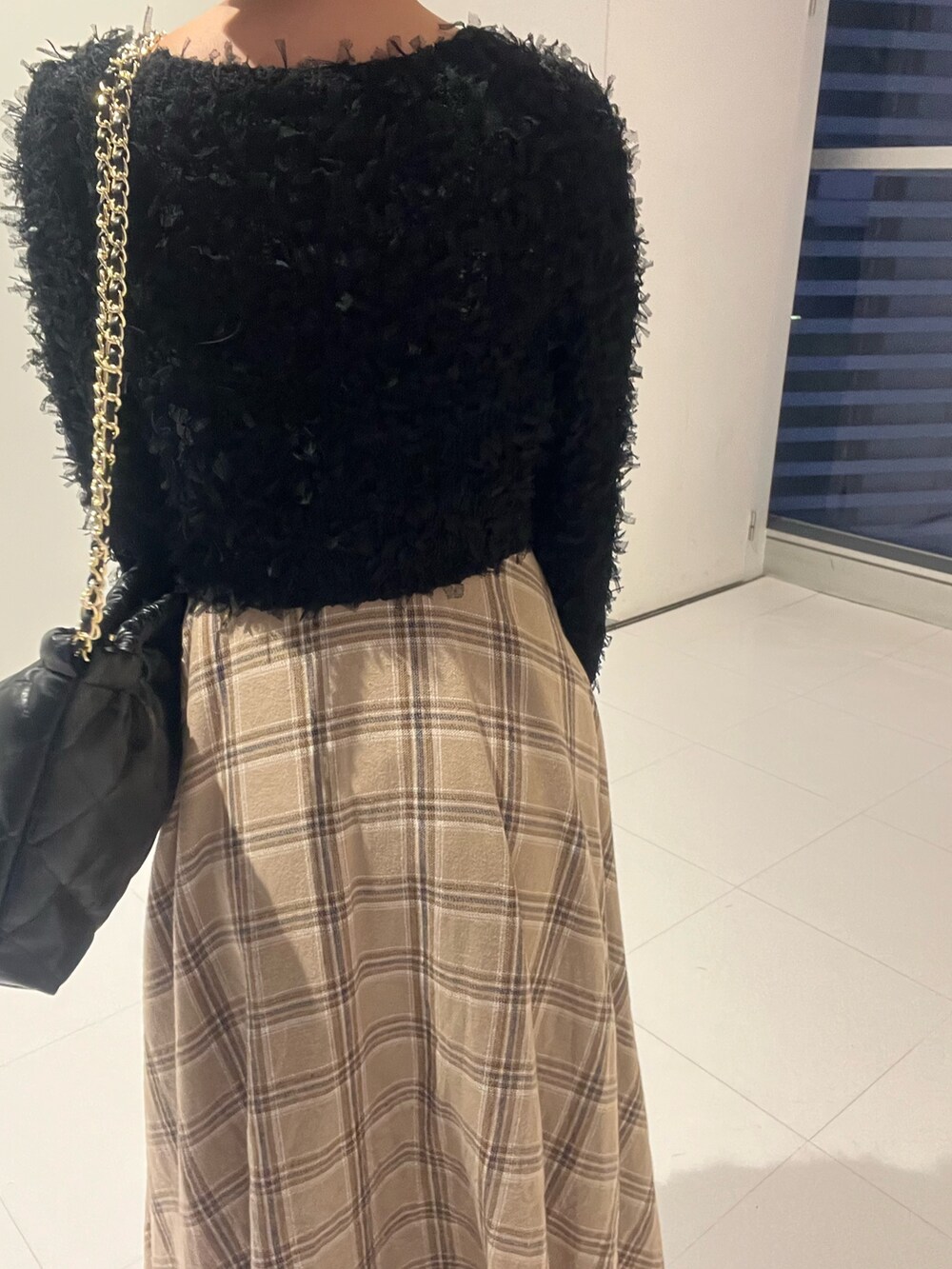 ブラック系のニット/セーター、ブラック系のワンピース、ブラック系のショルダーバッグを着用したレディースの秋コーディネートの6枚目の写真