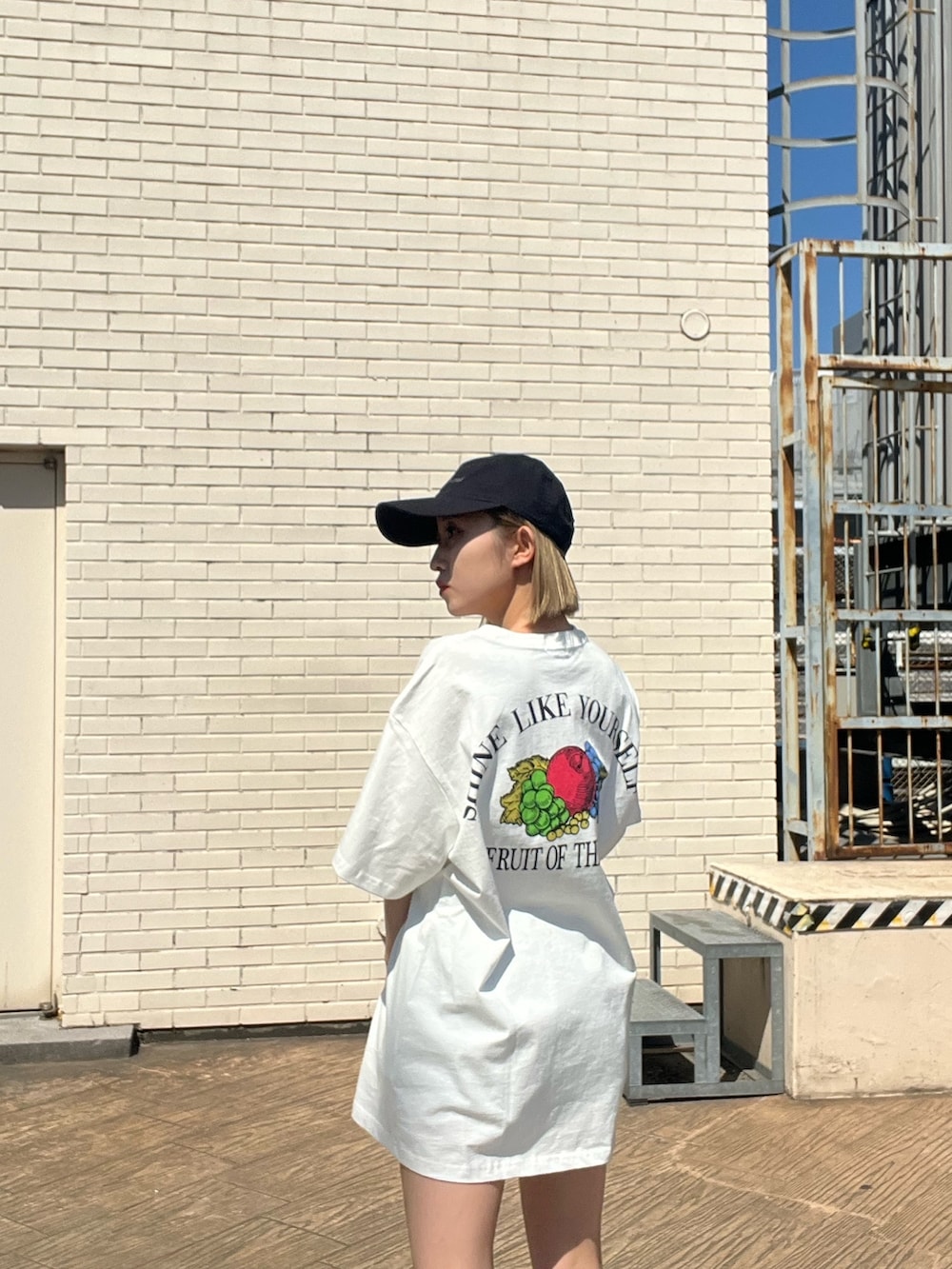 ホワイト系のTシャツ/カットソー、ブラック系のブーツ、ブラック系のキャップを着用したレディースの春コーディネートの7枚目の写真