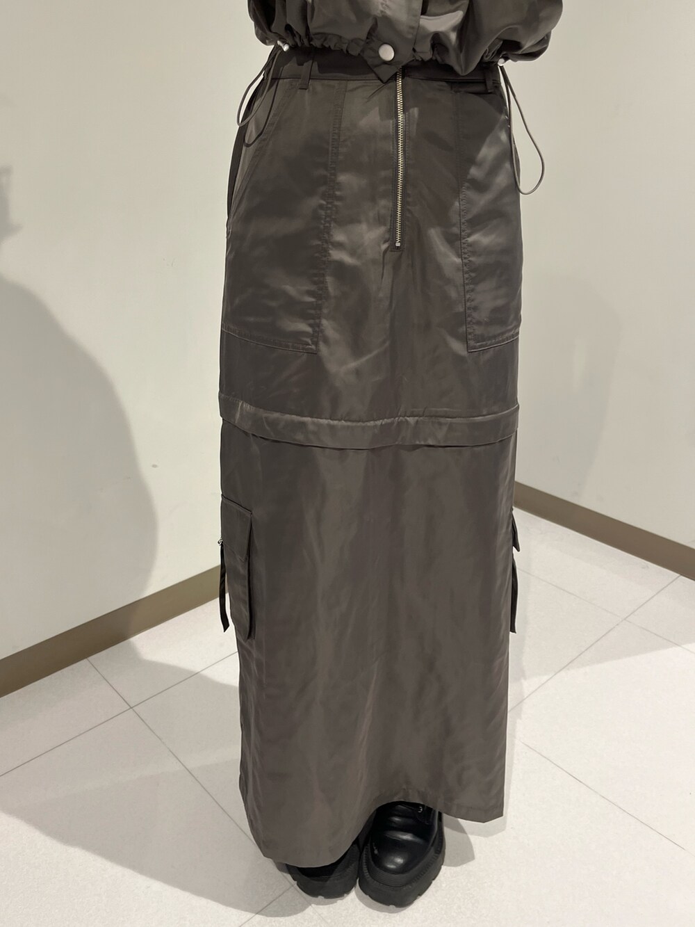 シルバー系のブーツ、グレー系のベスト、ホワイト系のスカートを着用したレディースの夏コーディネートの4枚目の写真