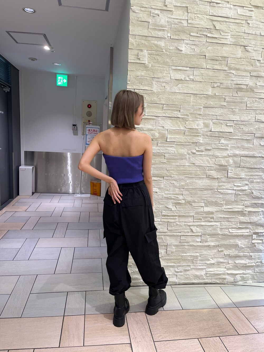 オレンジ系のカーゴパンツ、ブラック系のブーツ、パープル系のチューブトップを着用したレディースの春コーディネートの5枚目の写真