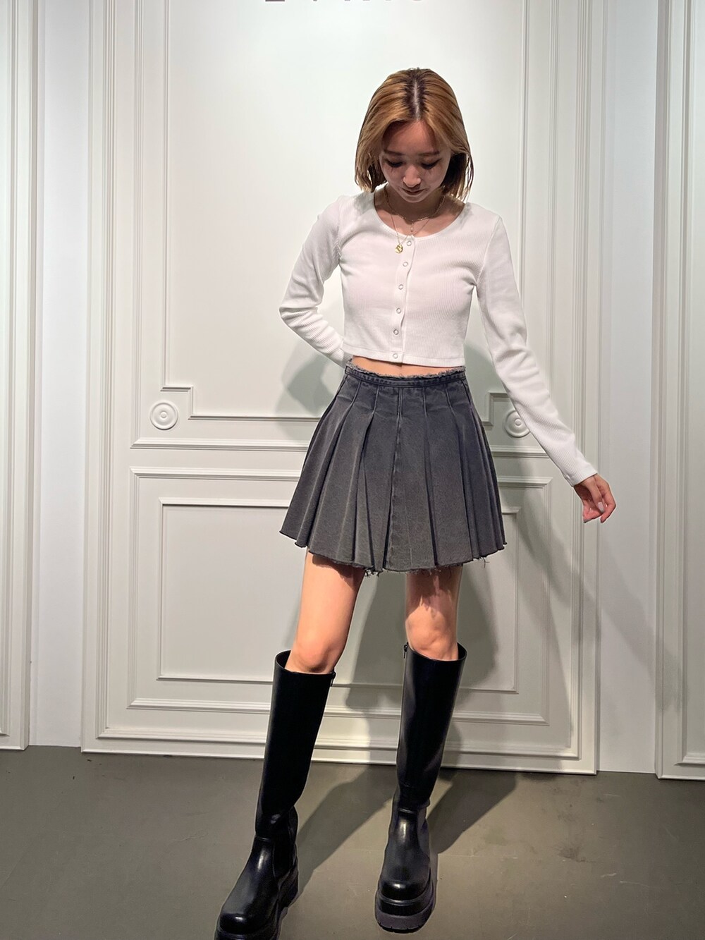 ホワイト系のTシャツ/カットソー、ブラック系のデニムスカート、ブラック系のブーツを着用したレディースの夏コーディネートの7枚目の写真