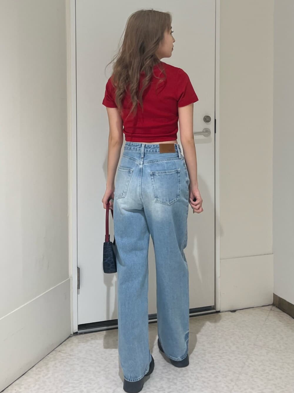 ブラック系のブーツ、ブラウン系のハンドバッグ、ブルー系のデニムパンツを着用したレディースの春コーディネートの4枚目の写真