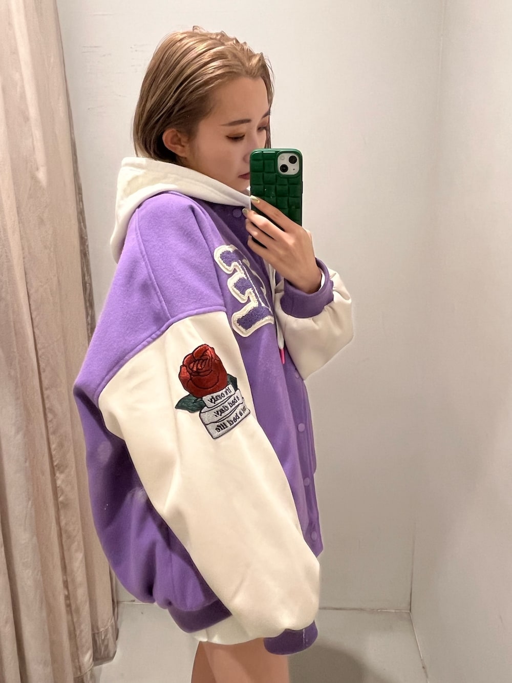 ホワイト系のパーカー、パープル系のスタジャン、ブラック系のブーツを着用したレディースの冬コーディネートの2枚目の写真