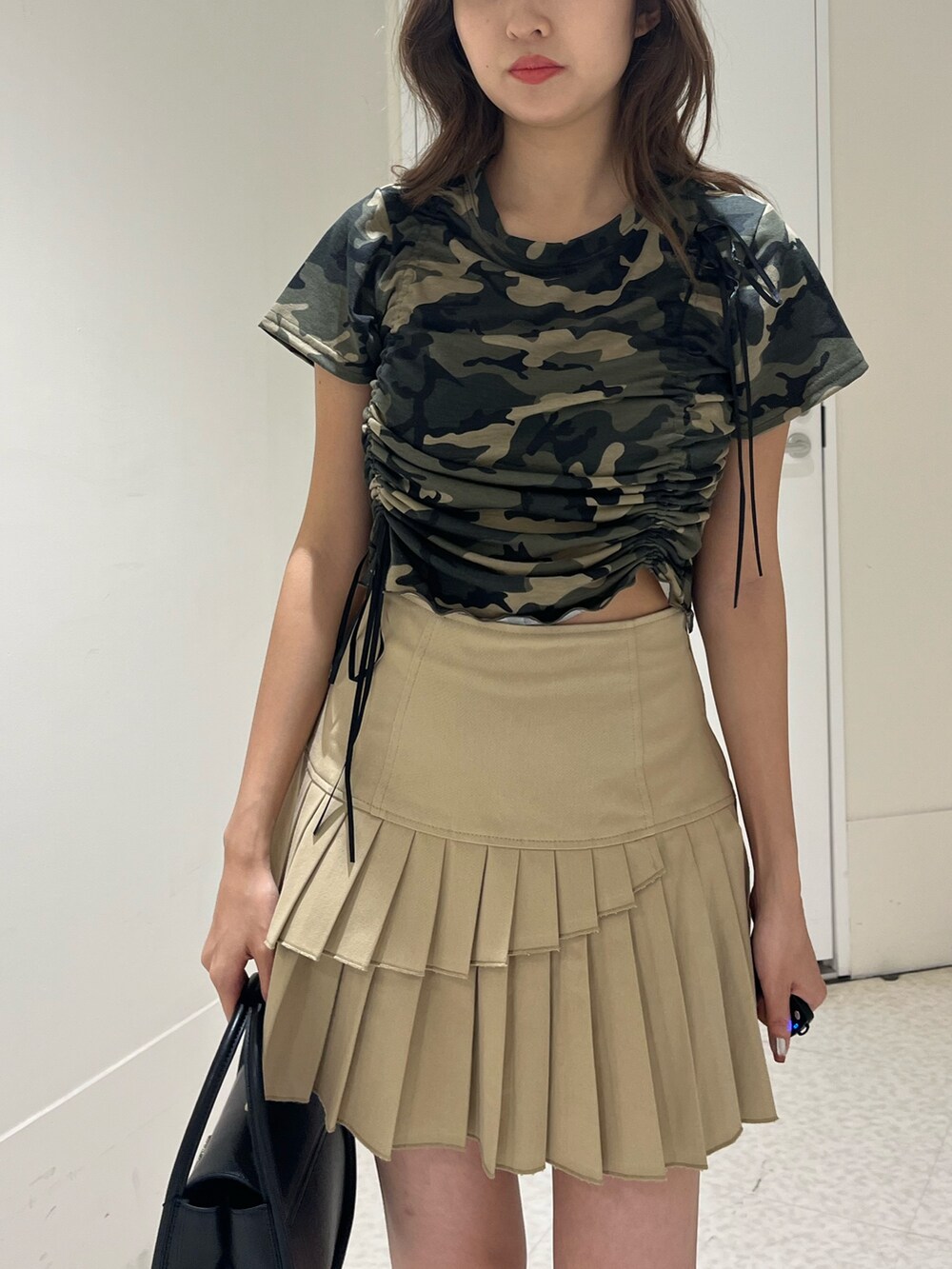 グリーン系のTシャツ/カットソー、ブラック系のブーツ、ベージュ系のスカートを着用したレディースの春コーディネートの5枚目の写真