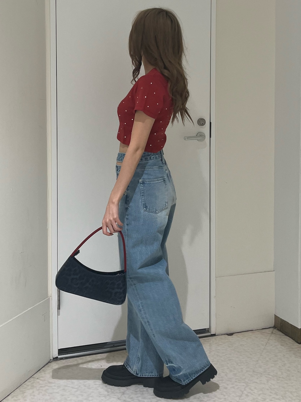 ブルー系のデニムパンツ、ブラウン系のハンドバッグ、ブラック系のブーツを着用したレディースの春コーディネートの2枚目の写真