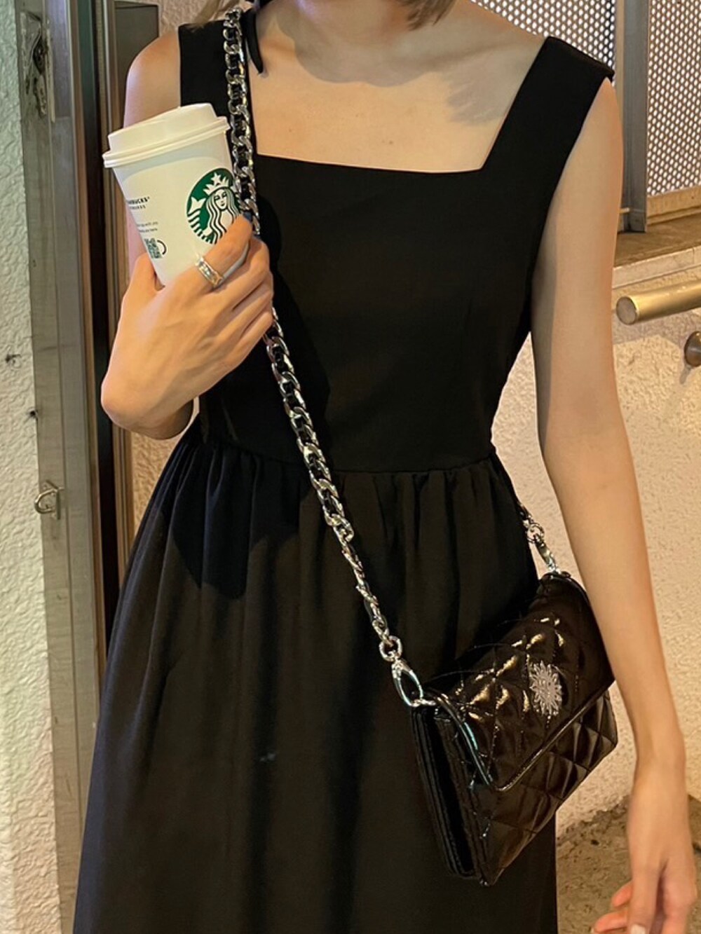 ブラック系のワンピース、ブラック系のショルダーバッグ、ホワイト系のサンダルを着用したレディースの夏コーディネートの3枚目の写真