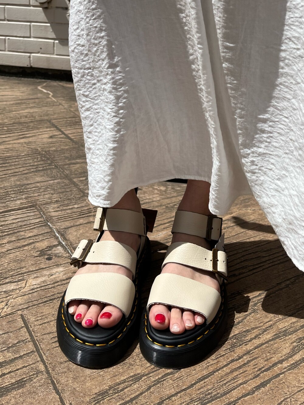 ホワイト系のワンピース、ベージュ系のサンダル、ブルー系のショルダーバッグを着用したレディースの春コーディネートの7枚目の写真