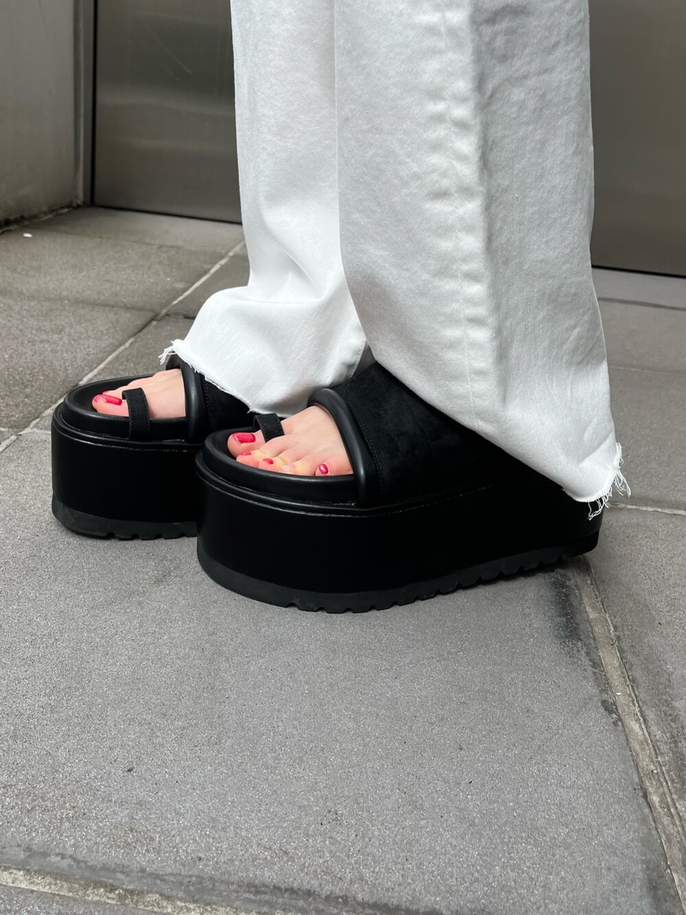 ブルー系のデニムパンツ、オレンジ系のタンクトップ、ブラック系のサンダルを着用したレディースの春コーディネートの8枚目の写真