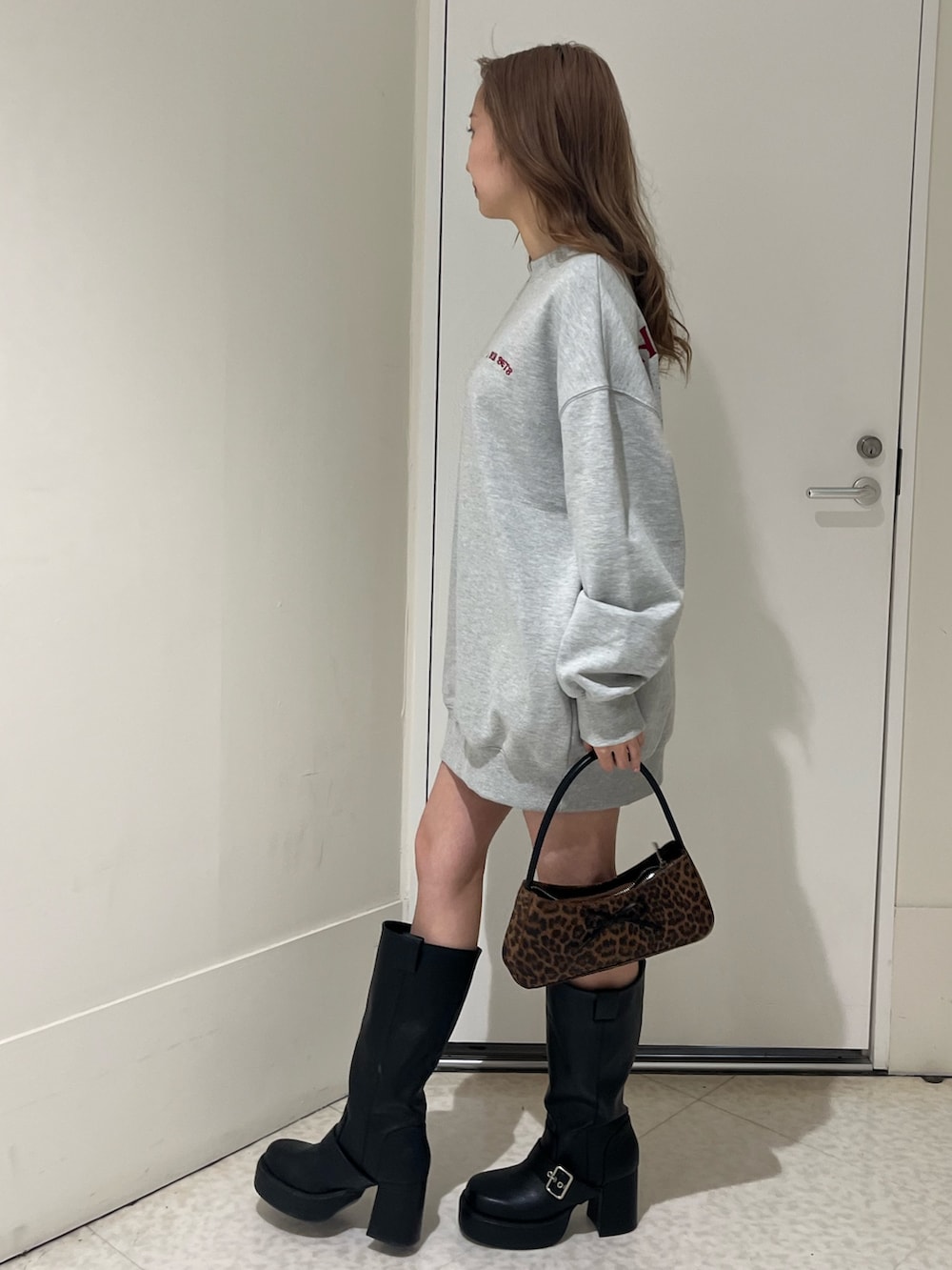 ブラック系のブーツ、ブラウン系のハンドバッグ、グレー系のスウェットを着用したレディースの春コーディネートの2枚目の写真