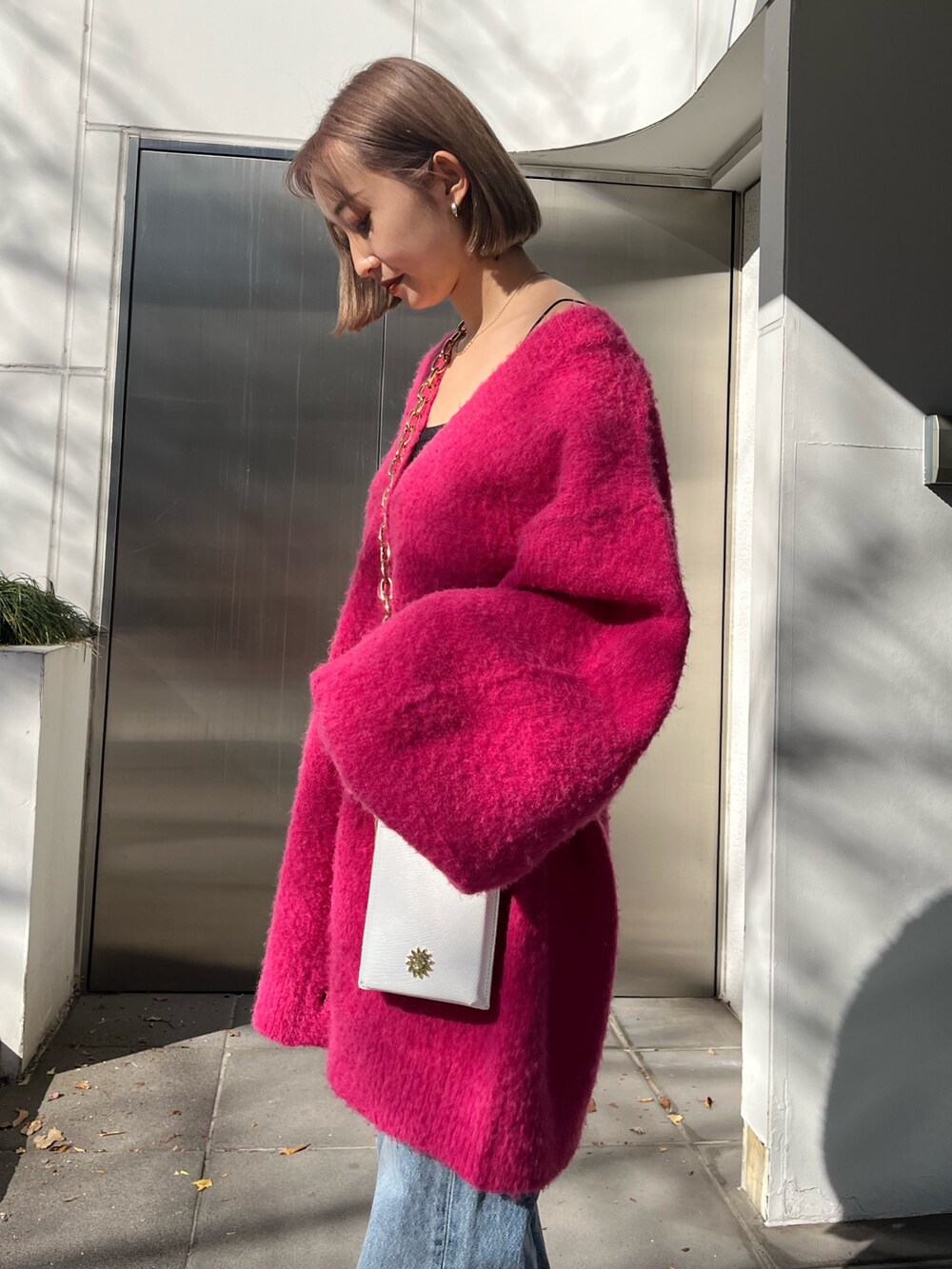 ブルー系のデニムパンツ、ホワイト系のショルダーバッグ、ピンク系のカーディガン/ボレロを着用したレディースの冬コーディネートの4枚目の写真