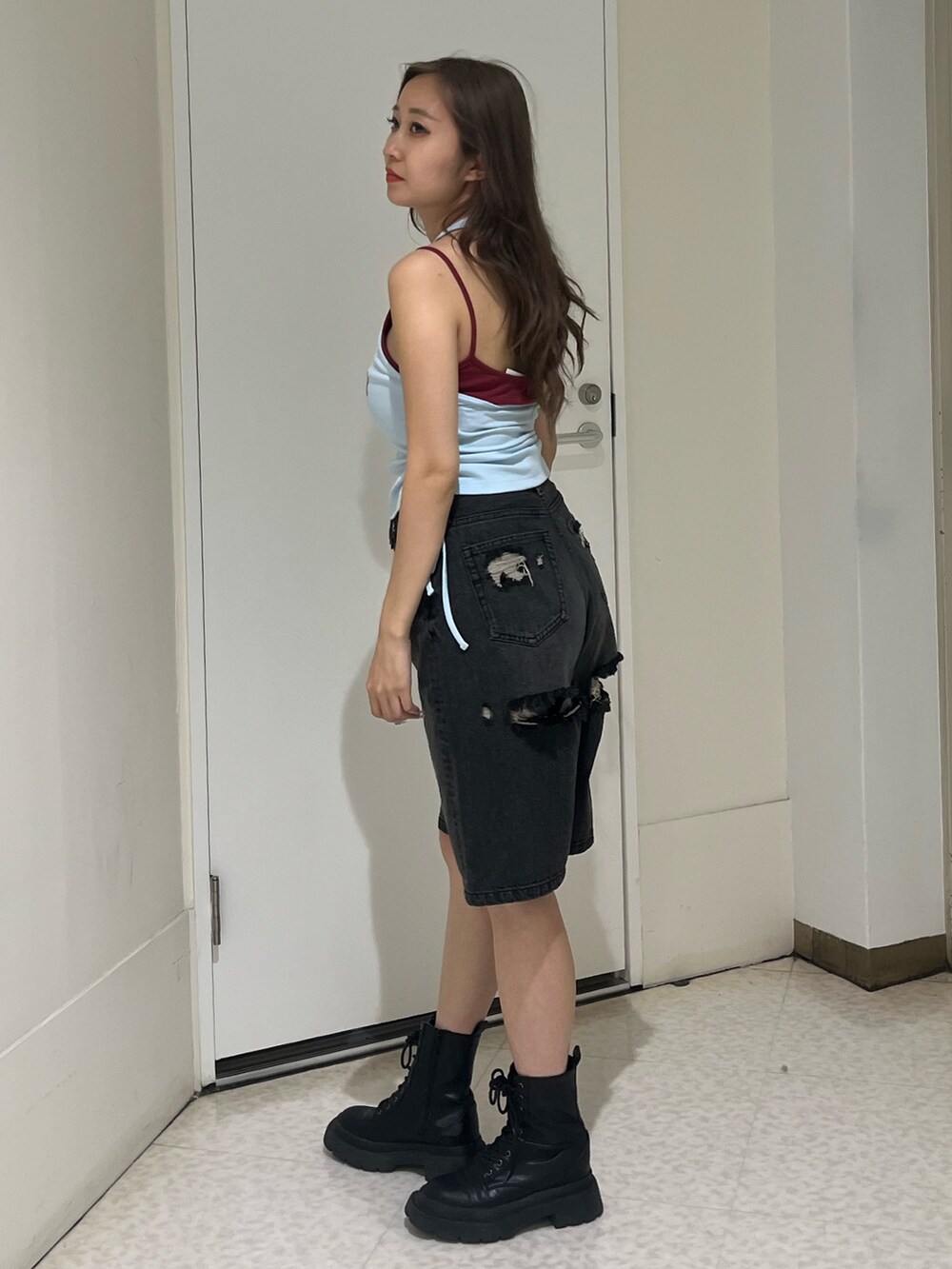 ブルー系のタンクトップ、ブラック系のデニムパンツ、ブラック系のブーツを着用したレディースの夏コーディネートの2枚目の写真