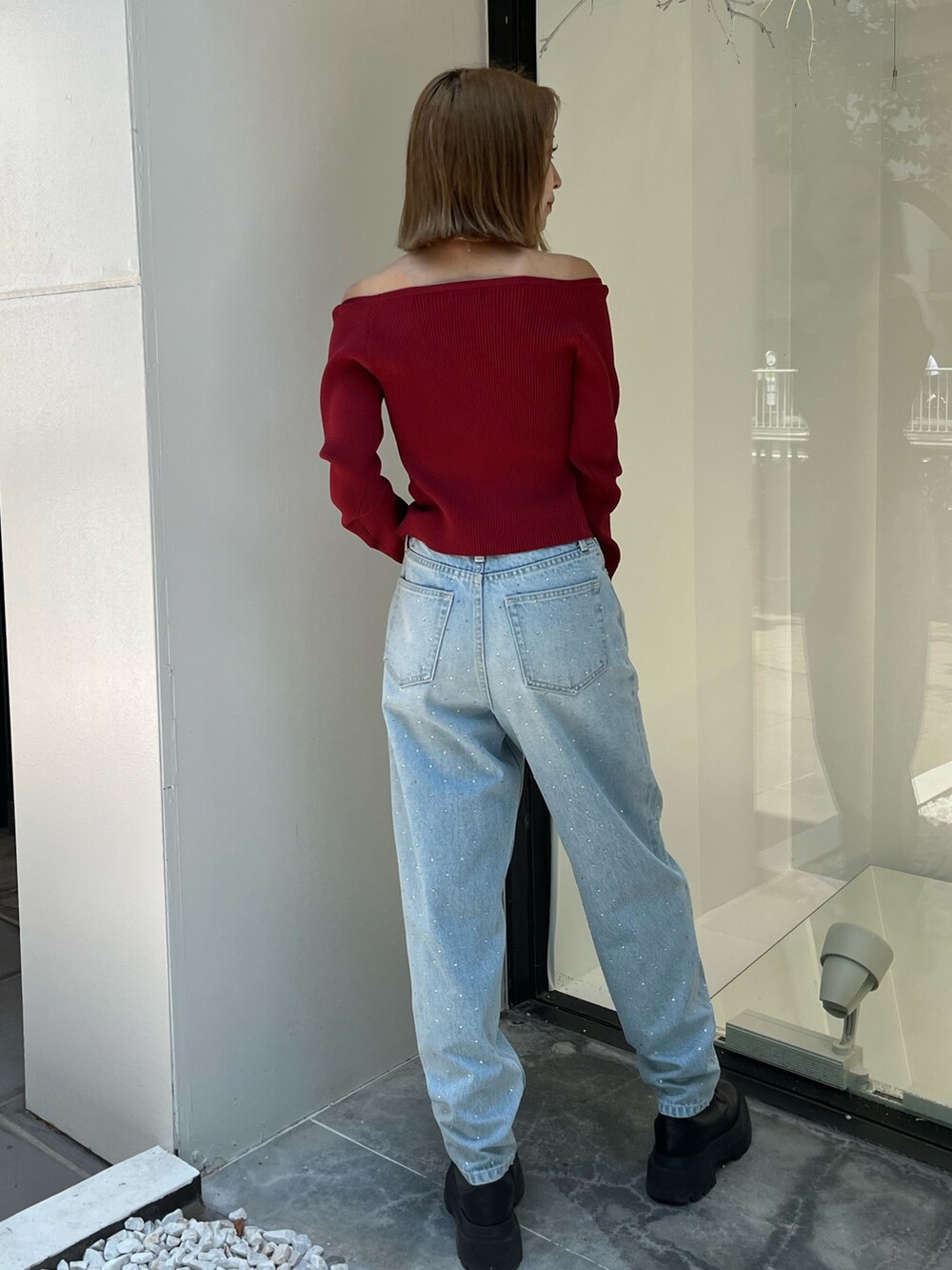 ブルー系のデニムパンツ、レッド系のニット/セーター、ブルー系のハンドバッグを着用したレディースの秋コーディネートの4枚目の写真