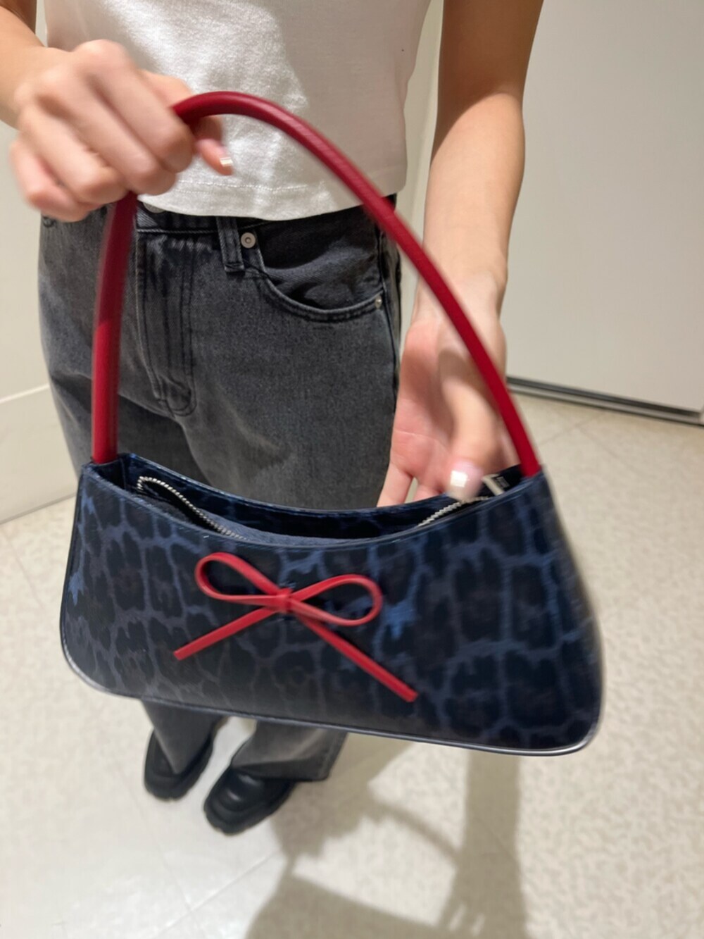 ブラック系のブーツ、ブラウン系のハンドバッグ、ブラック系のデニムパンツを着用したレディースの春コーディネートの4枚目の写真