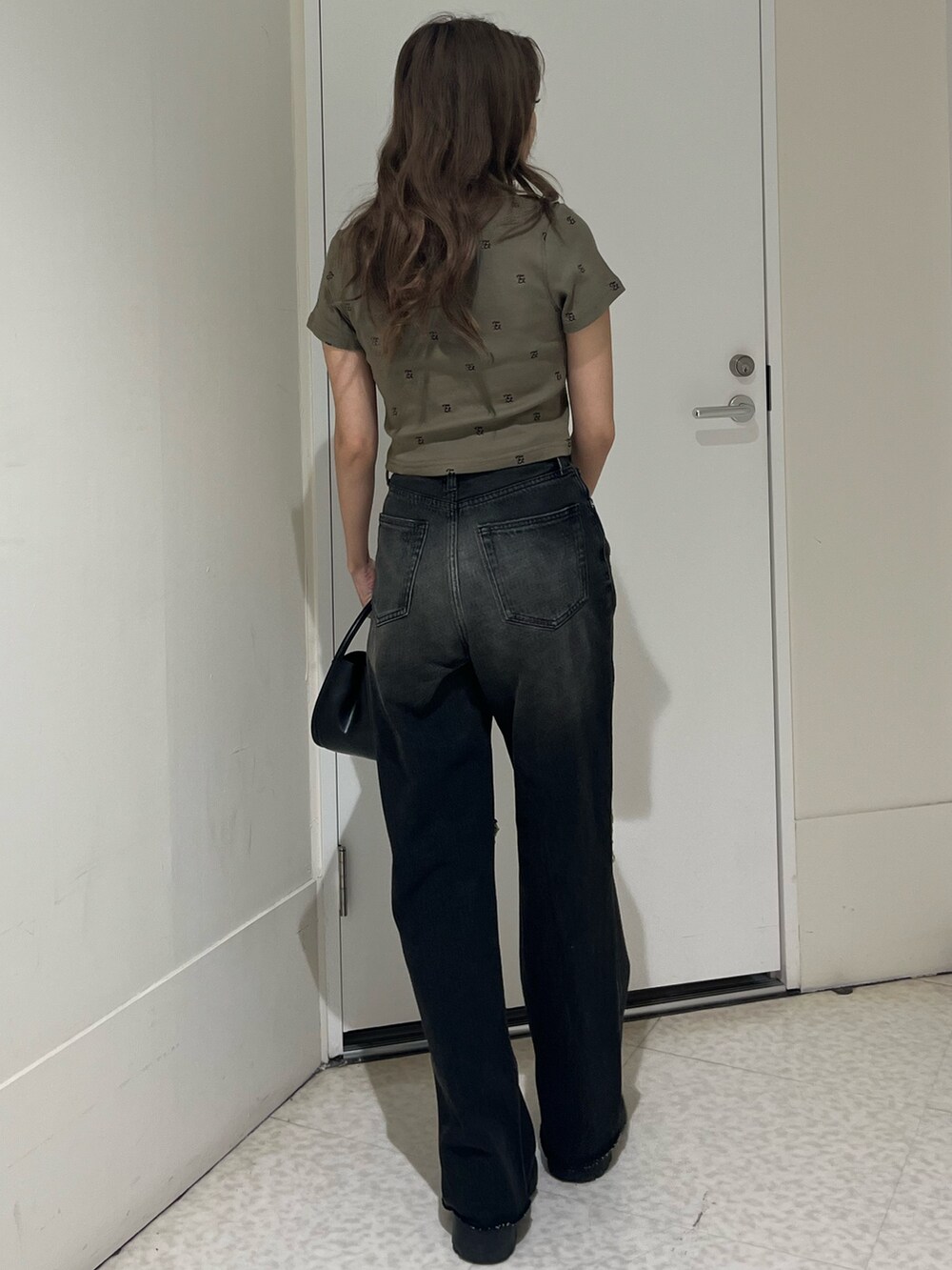 グリーン系のTシャツ/カットソー、ブラック系のブーツ、ブラック系のハンドバッグを着用したレディースの春コーディネートの3枚目の写真