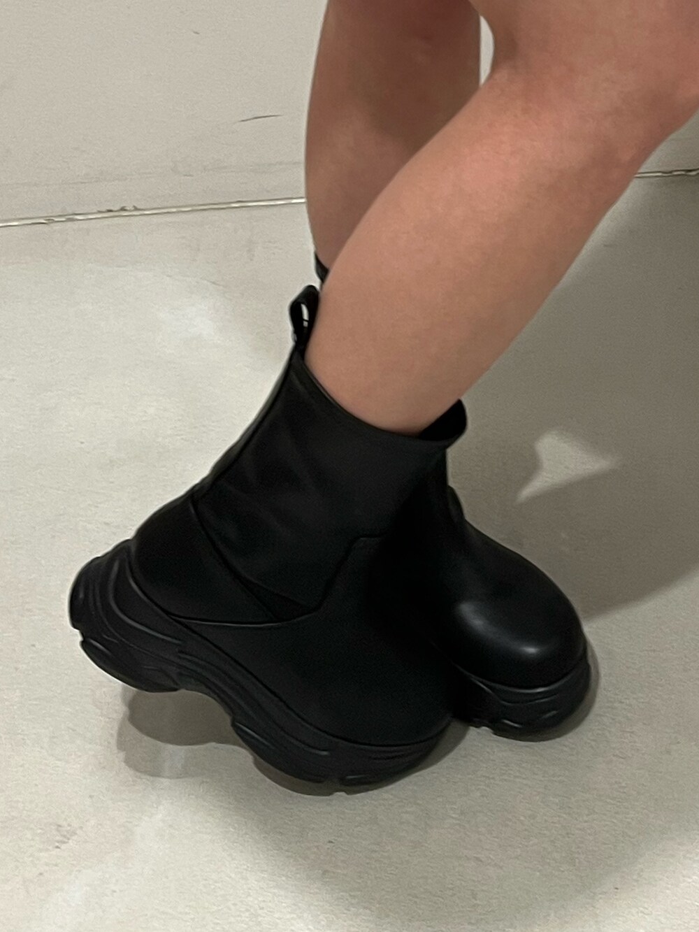 パープル系のニット/セーター、ブラック系のブーツ、ブラック系のベルトを着用したレディースの冬コーディネートの6枚目の写真