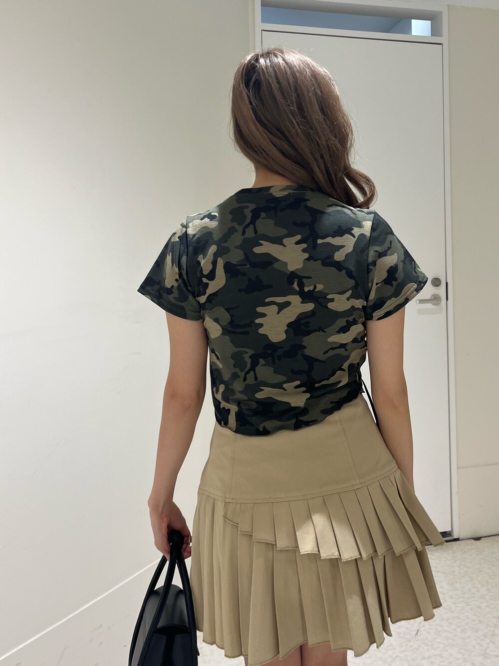 グリーン系のTシャツ/カットソー、ブラック系のブーツ、ベージュ系のスカートを着用したレディースの春コーディネートの6枚目の写真