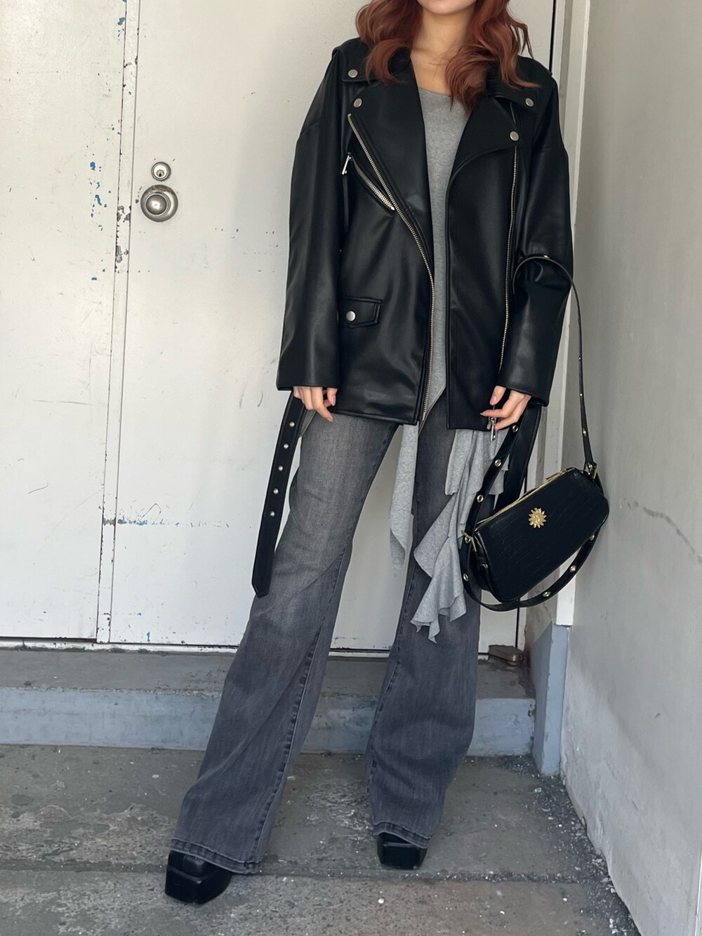 グリーン系のワンピース、イエロー系のライダースジャケット、ブラック系のデニムパンツを着用したレディースの春コーディネートの7枚目の写真