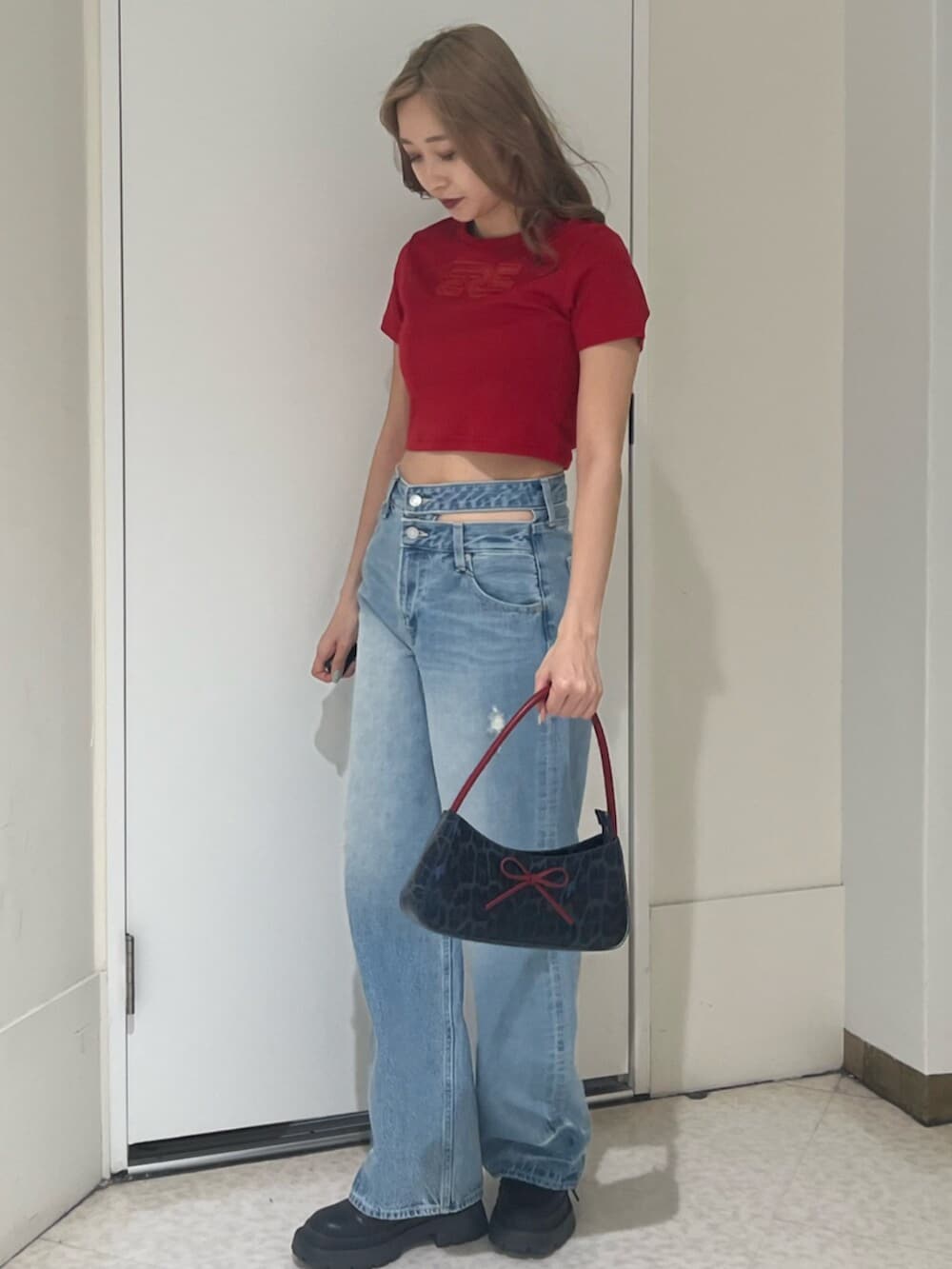 ブラック系のブーツ、ブラウン系のハンドバッグ、ブルー系のデニムパンツを着用したレディースの春コーディネートの2枚目の写真