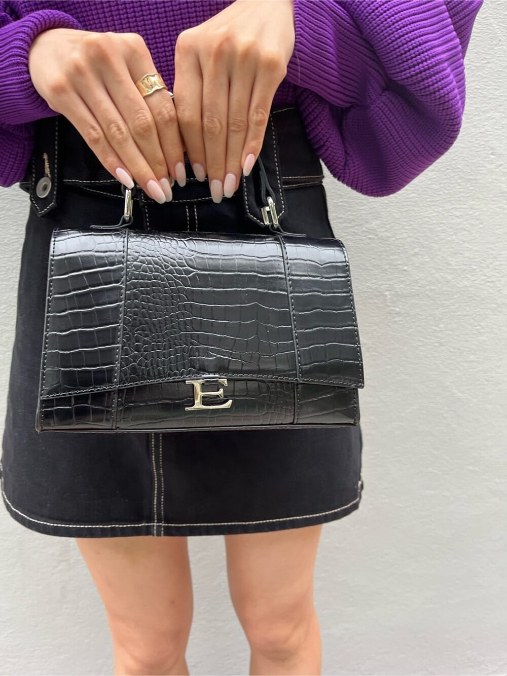 ブラック系のブーツ、ブラック系のデニムスカート、パープル系のニット/セーターを着用したレディースの秋コーディネートの5枚目の写真