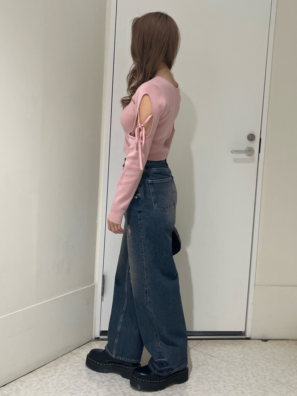 ブルー系のデニムパンツ、ピンク系のニット/セーター、ブラック系のボストンバッグを着用したレディースの春コーディネートの2枚目の写真