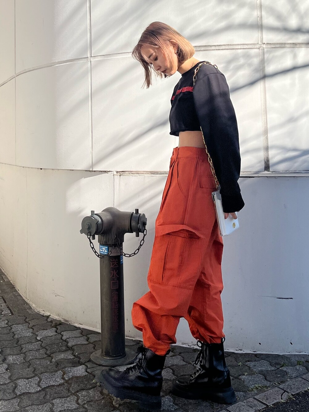 オレンジ系のカーゴパンツ、ホワイト系のブーツ、ブラック系のTシャツ/カットソーを着用したレディースの冬コーディネートの7枚目の写真