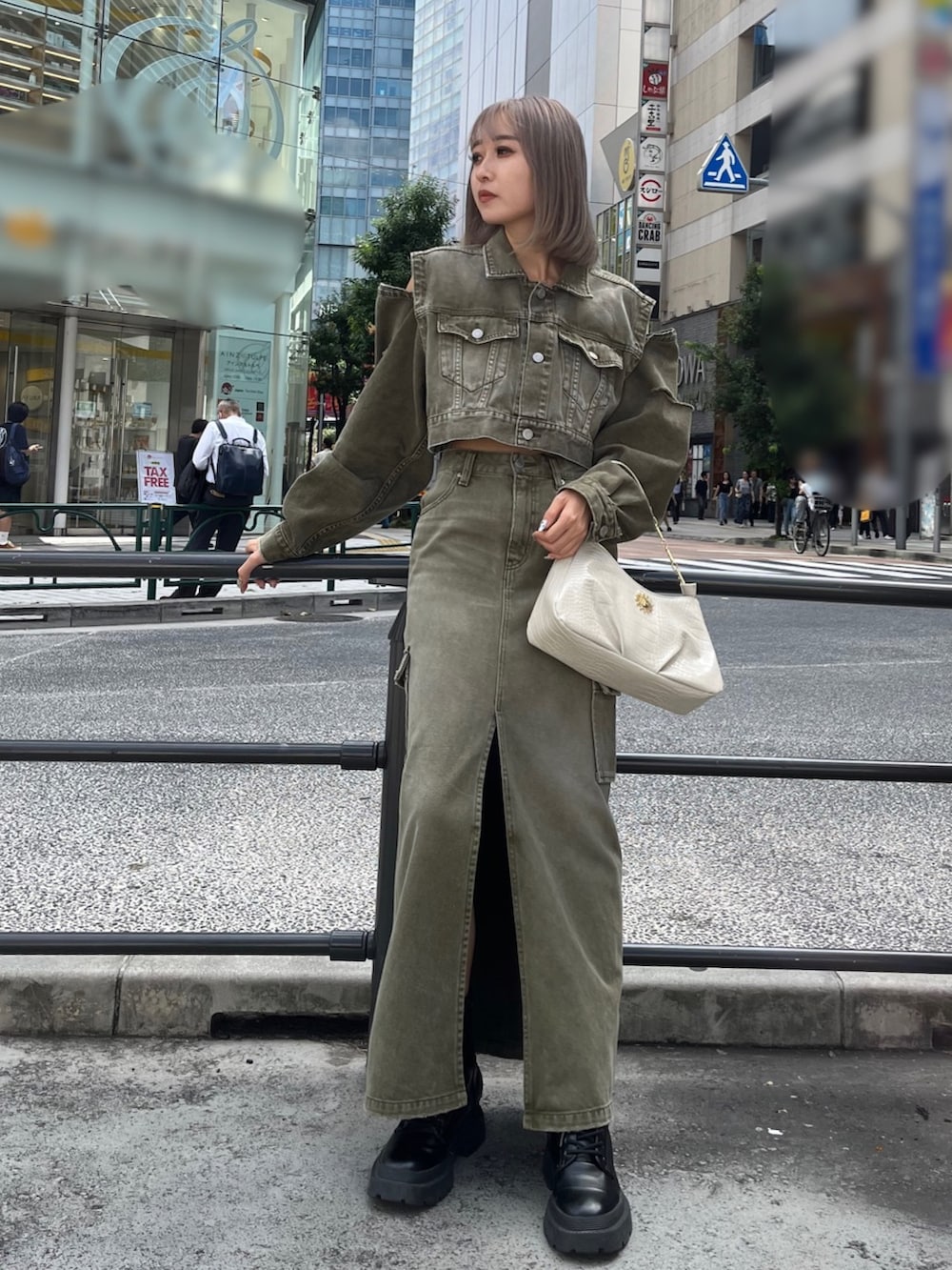 グリーン系のデニムジャケット、グリーン系のデニムスカート、ブラック系のハンドバッグを着用したレディースの秋コーディネートの2枚目の写真