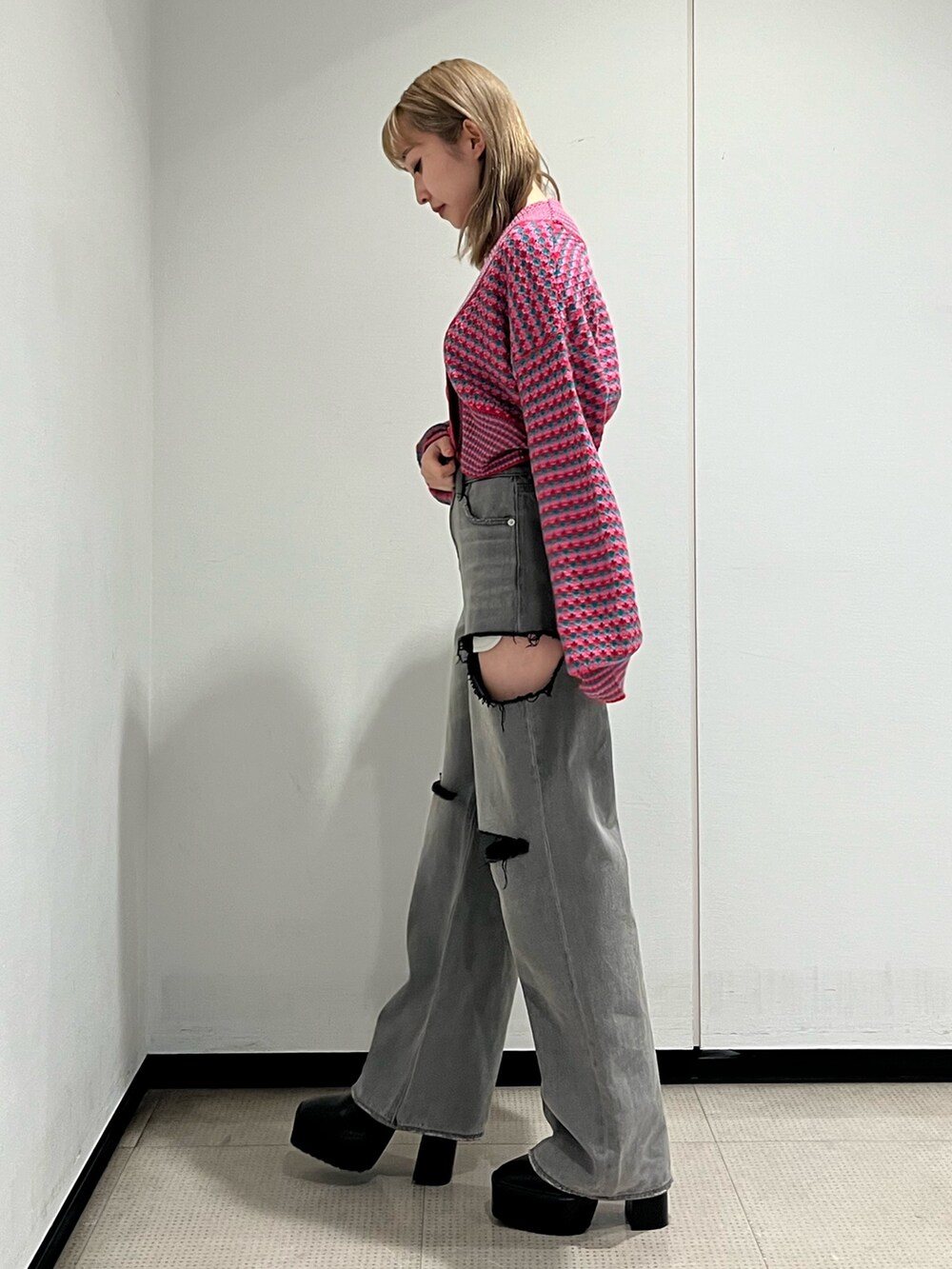 ブラック系のデニムパンツ、ピンク系のカーディガン/ボレロ、ブラック系のブーツを着用したレディースの冬コーディネートの2枚目の写真