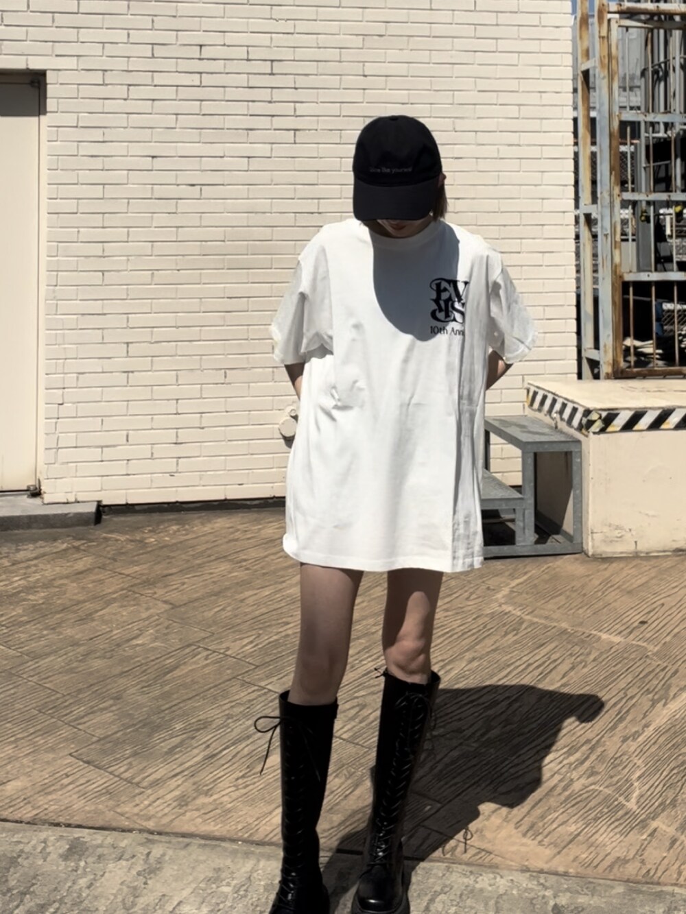 ホワイト系のTシャツ/カットソー、ブラック系のブーツ、ブラック系のキャップを着用したレディースの春コーディネートの2枚目の写真