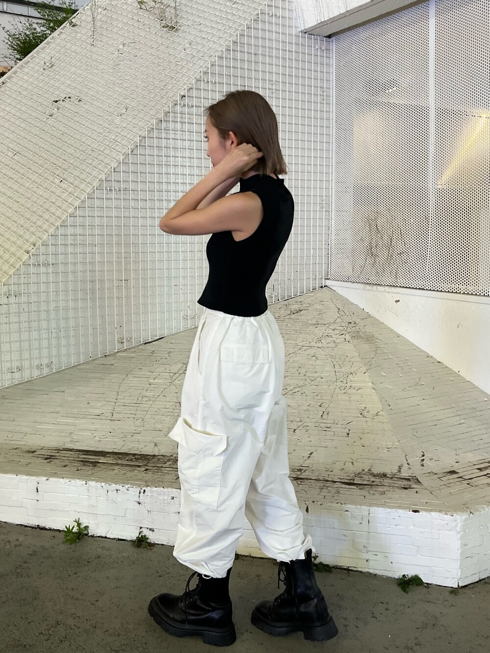 ホワイト系のカーゴパンツ、ブラック系のタンクトップ、ホワイト系のブーツを着用したレディースの夏コーディネートの5枚目の写真