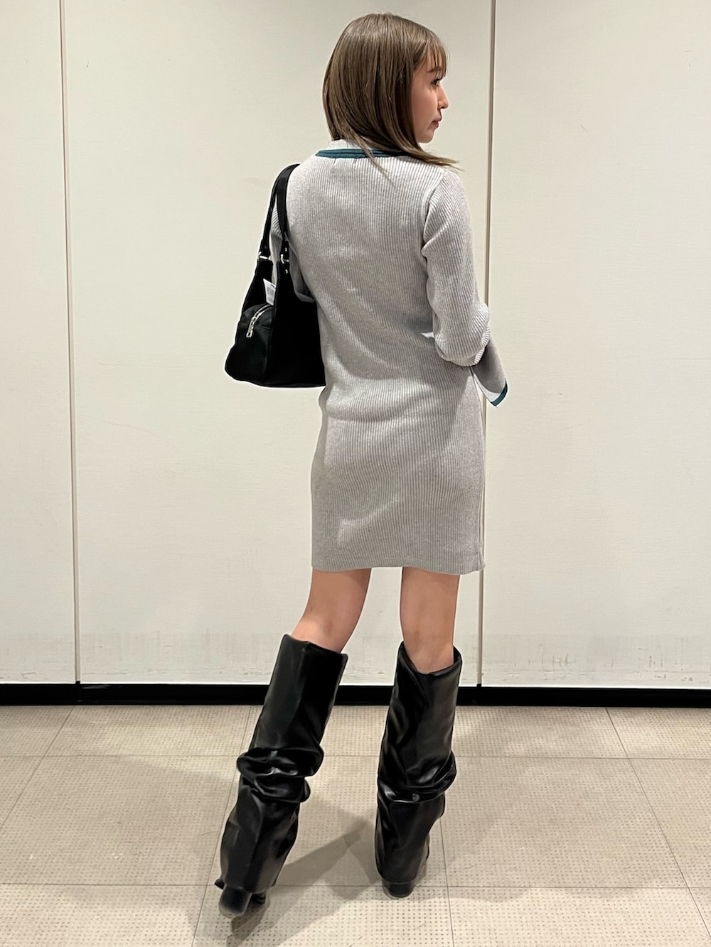 ブラック系のブーツ、グレー系のワンピース、ブラック系のハンドバッグを着用したレディースの冬コーディネートの3枚目の写真