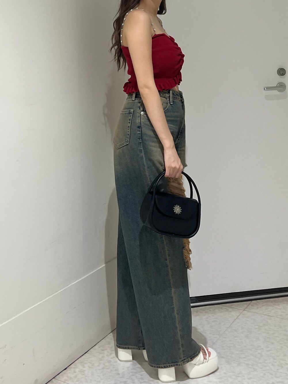 ブルー系のデニムパンツ、ブラック系のハンドバッグ、ブラック系のサンダルを着用したレディースの夏コーディネートの5枚目の写真