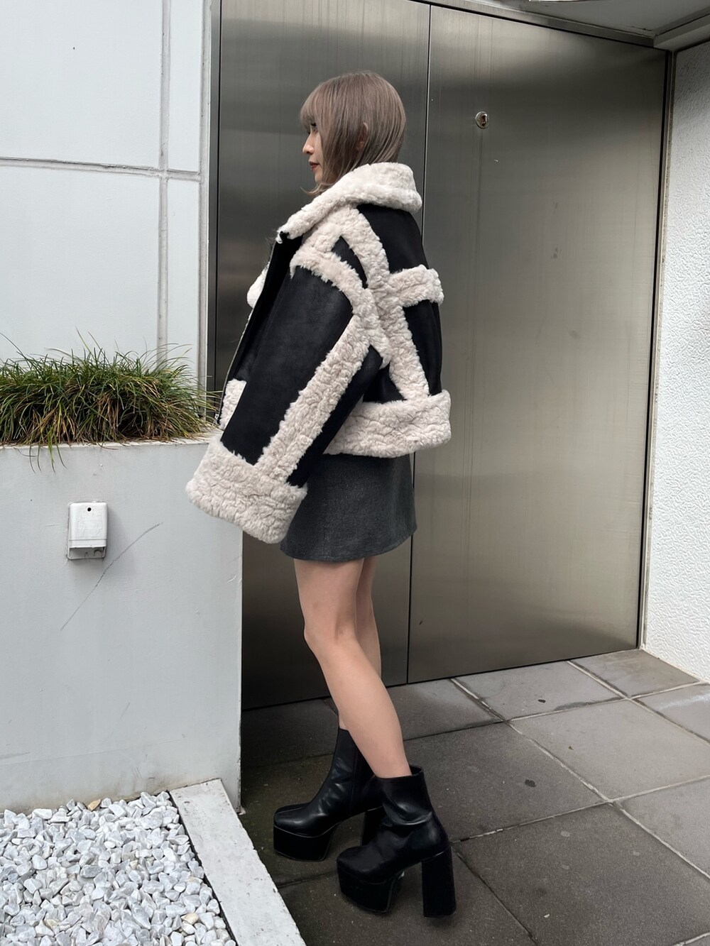 ブラック系のブーツ、ブラック系のショルダーバッグ、グリーン系のムートンコートを着用したレディースの冬コーディネートの4枚目の写真