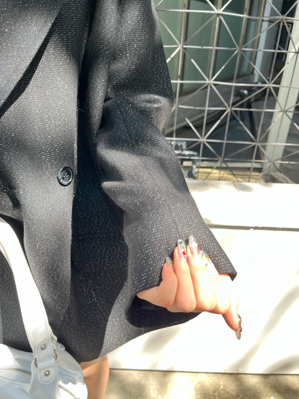 ブラック系のテーラードジャケット、ブラック系のスカート、ブラック系のブーツを着用したレディースの秋コーディネートの5枚目の写真