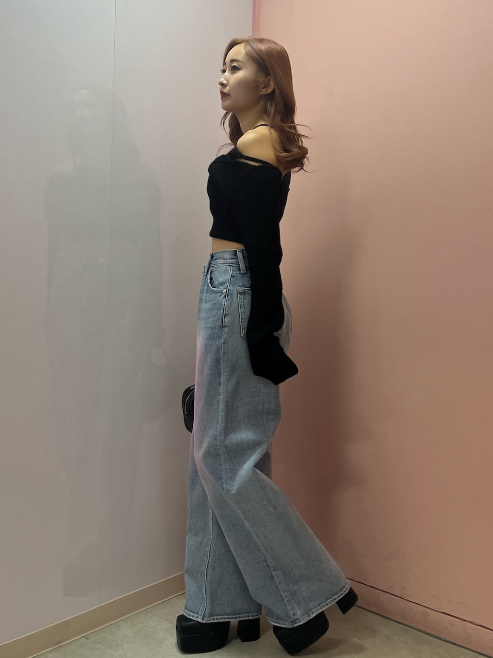 ブラック系のボストンバッグ、ブラック系のブーツ、イエロー系のニット/セーターを着用したレディースの春コーディネートの2枚目の写真