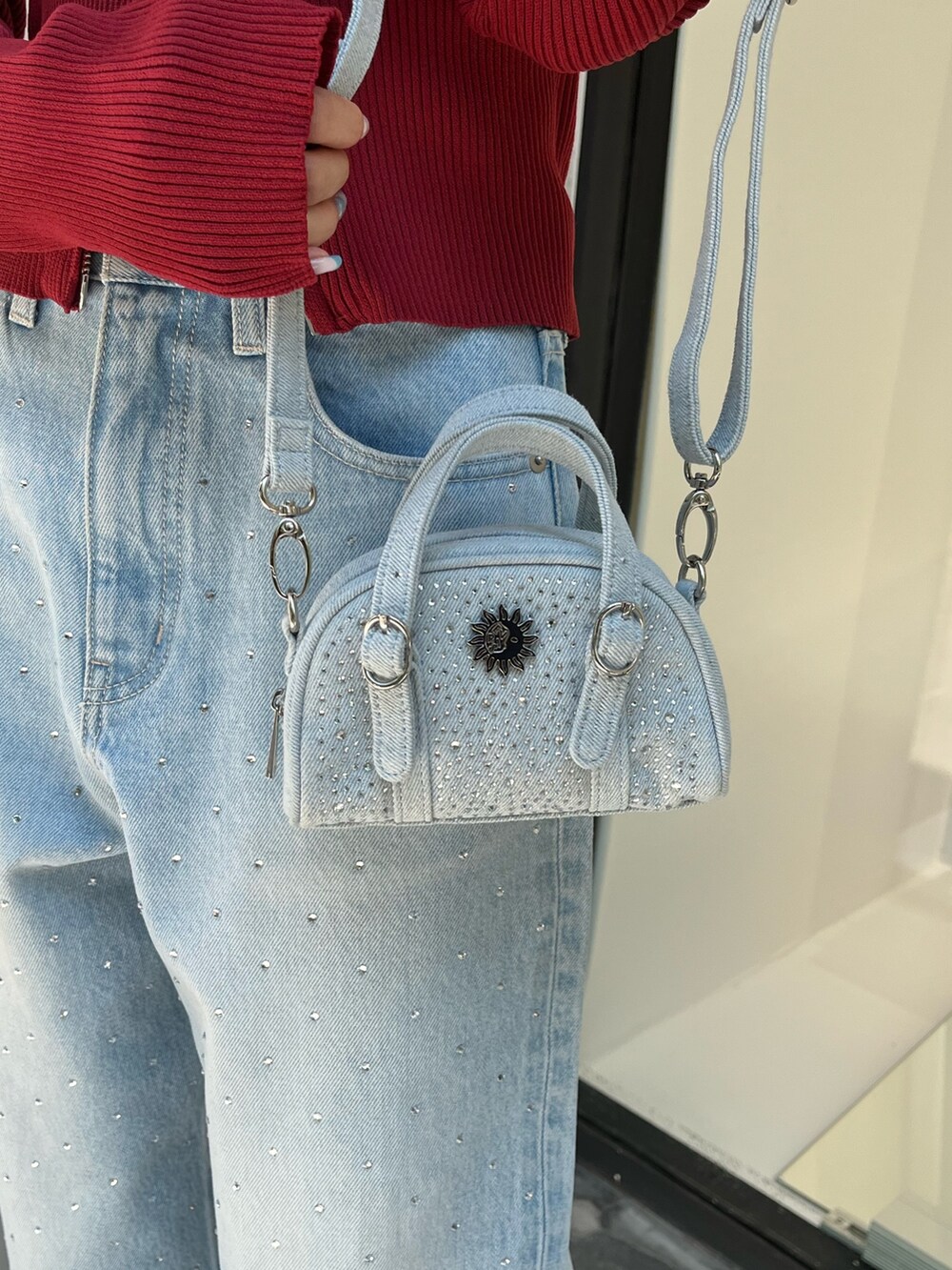 ブルー系のデニムパンツ、レッド系のニット/セーター、ブルー系のハンドバッグを着用したレディースの秋コーディネートの5枚目の写真