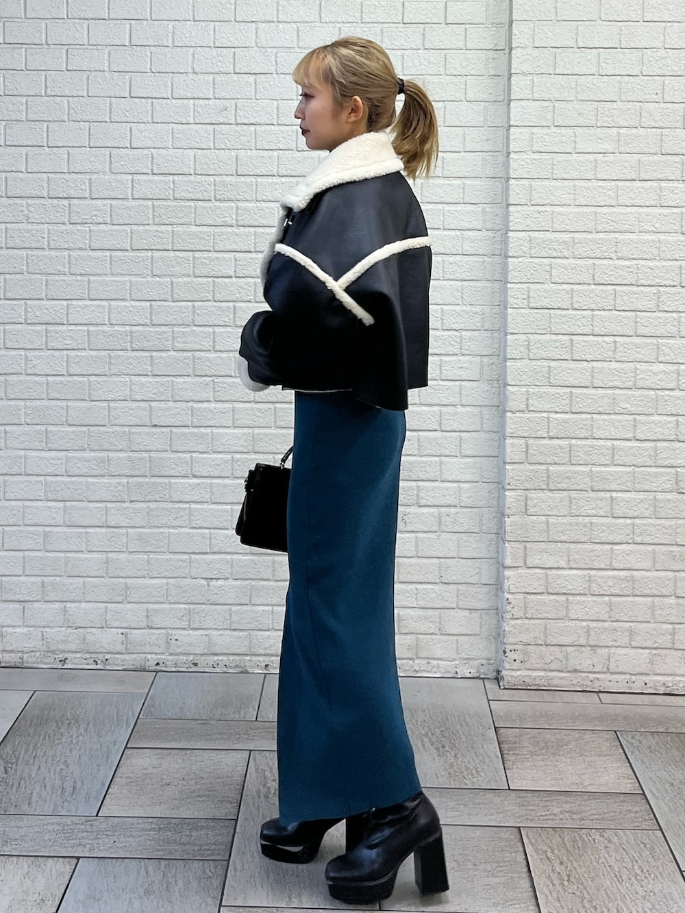 ブラック系のブルゾン、ブラック系のショルダーバッグ、ブルー系のワンピースを着用したレディースの冬コーディネートの2枚目の写真